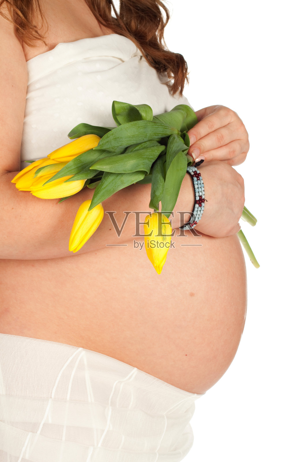 怀孕的肚子和黄色的郁金香。照片摄影图片
