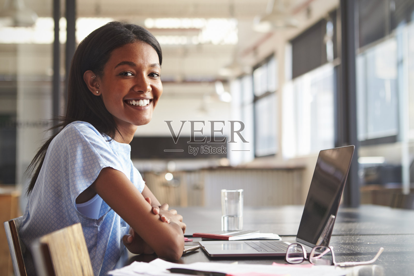 年轻黑人女性在办公室用笔记本电脑对着镜头微笑照片摄影图片
