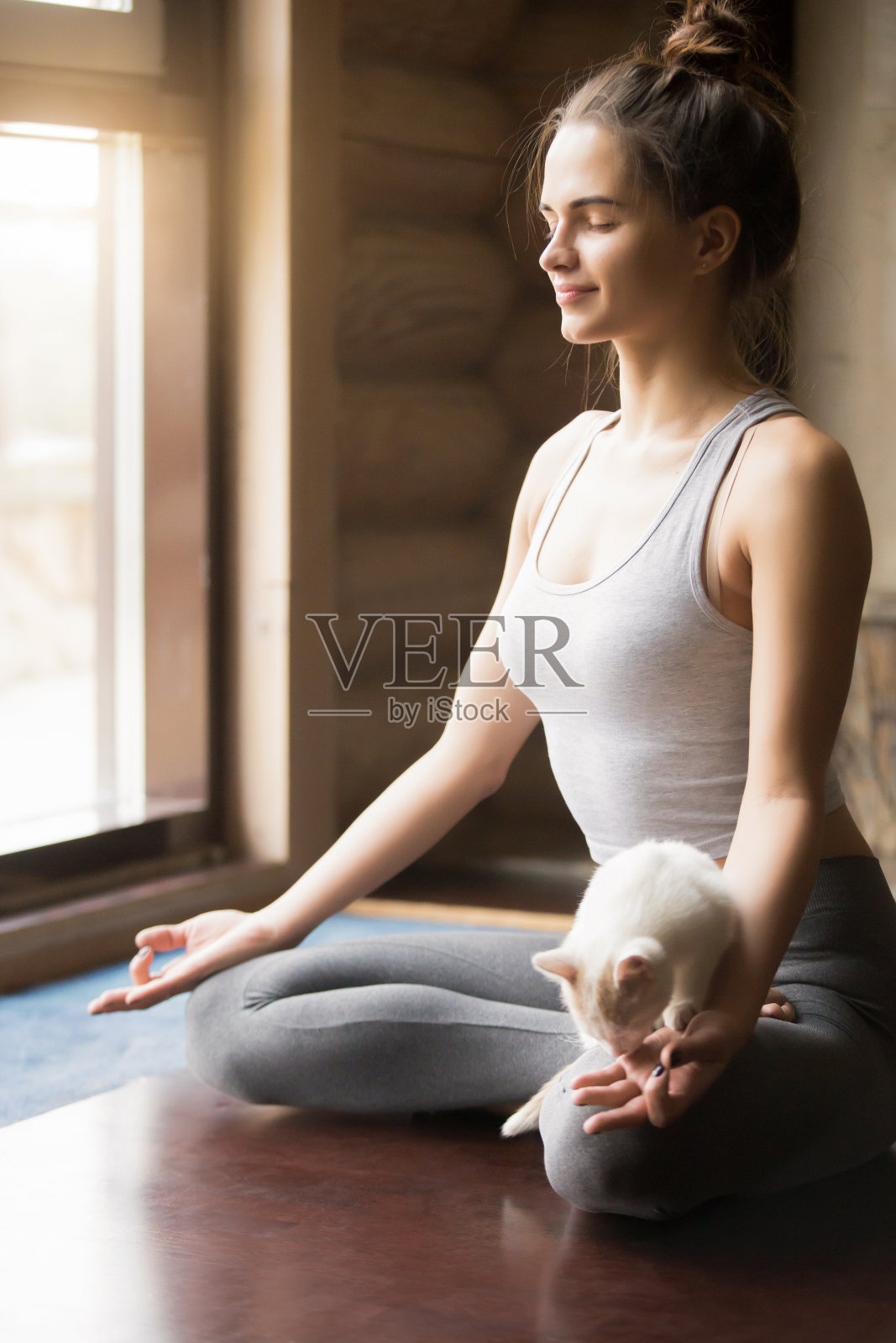 年轻的瑜伽女子在半莲花姿势，家庭内部背景照片摄影图片