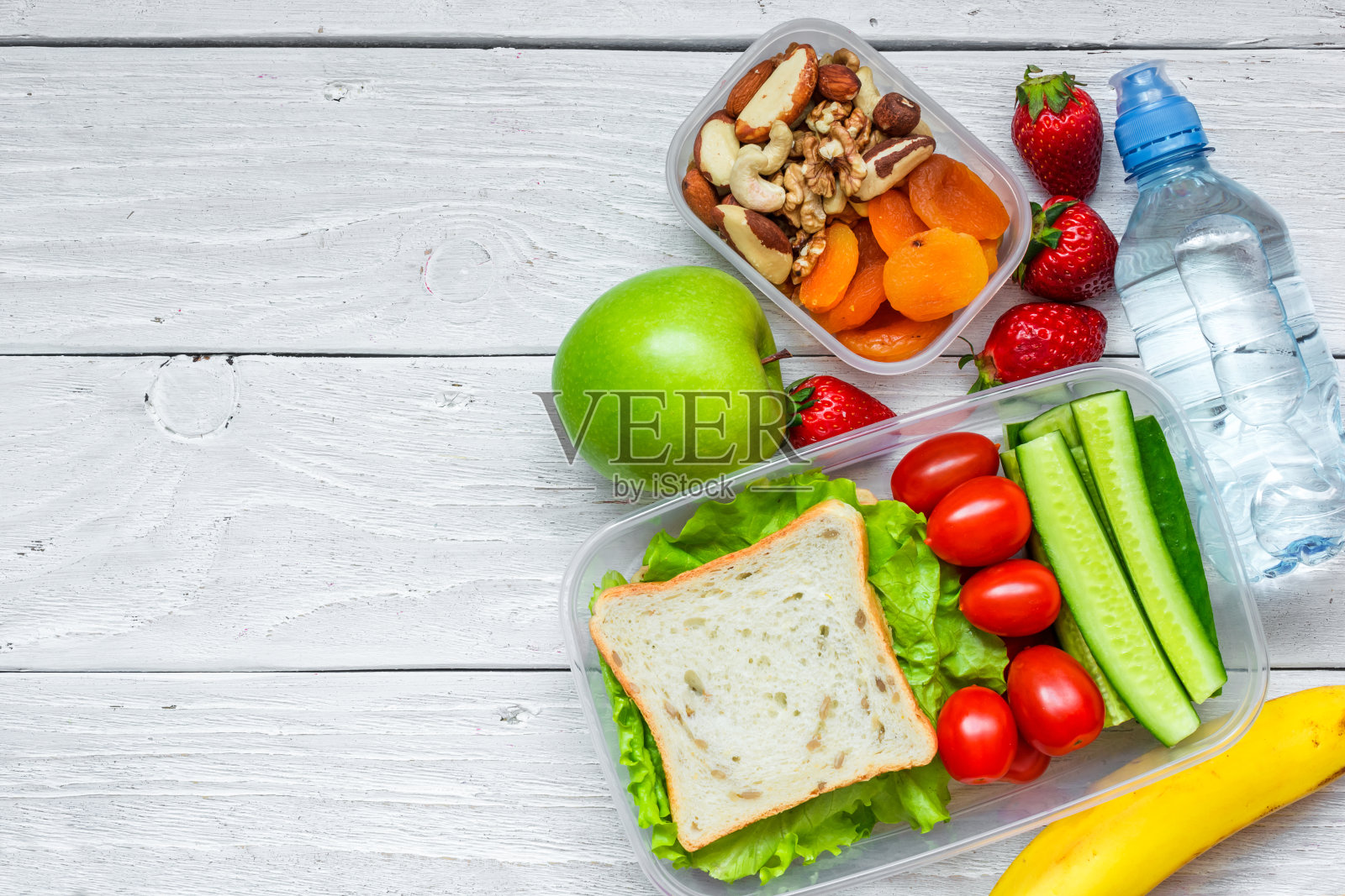 学校午餐盒有三明治和新鲜蔬菜，一瓶水，坚果和水果照片摄影图片