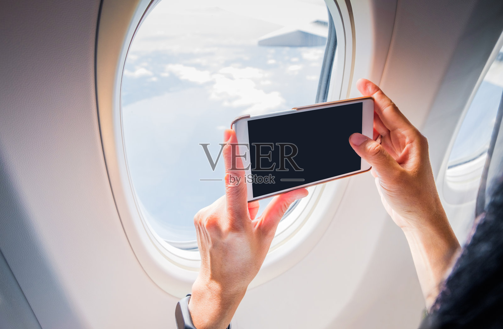 靠近拿着手机的女人，在飞机窗外拍照，空白屏幕添加你的设计照片摄影图片