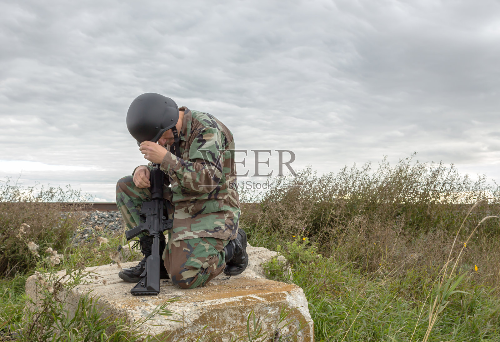 士兵跪在巨石上祈祷照片摄影图片