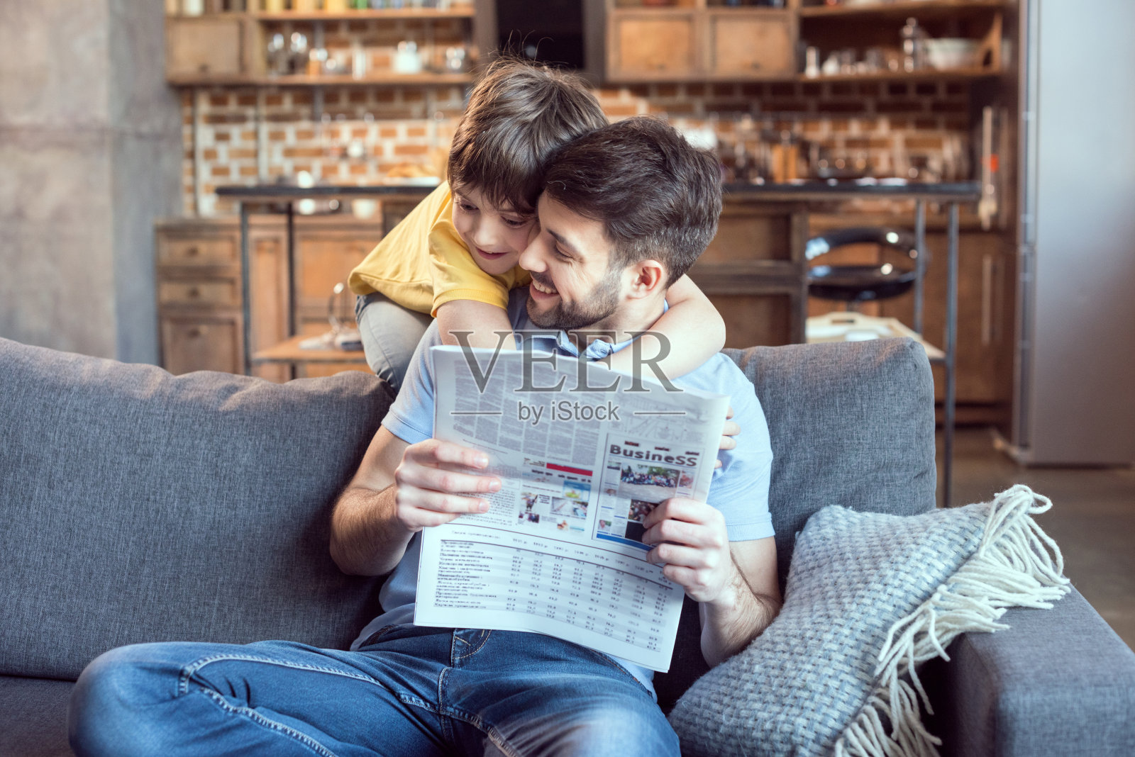 快乐的小男孩抱着爸爸在家里看报纸照片摄影图片