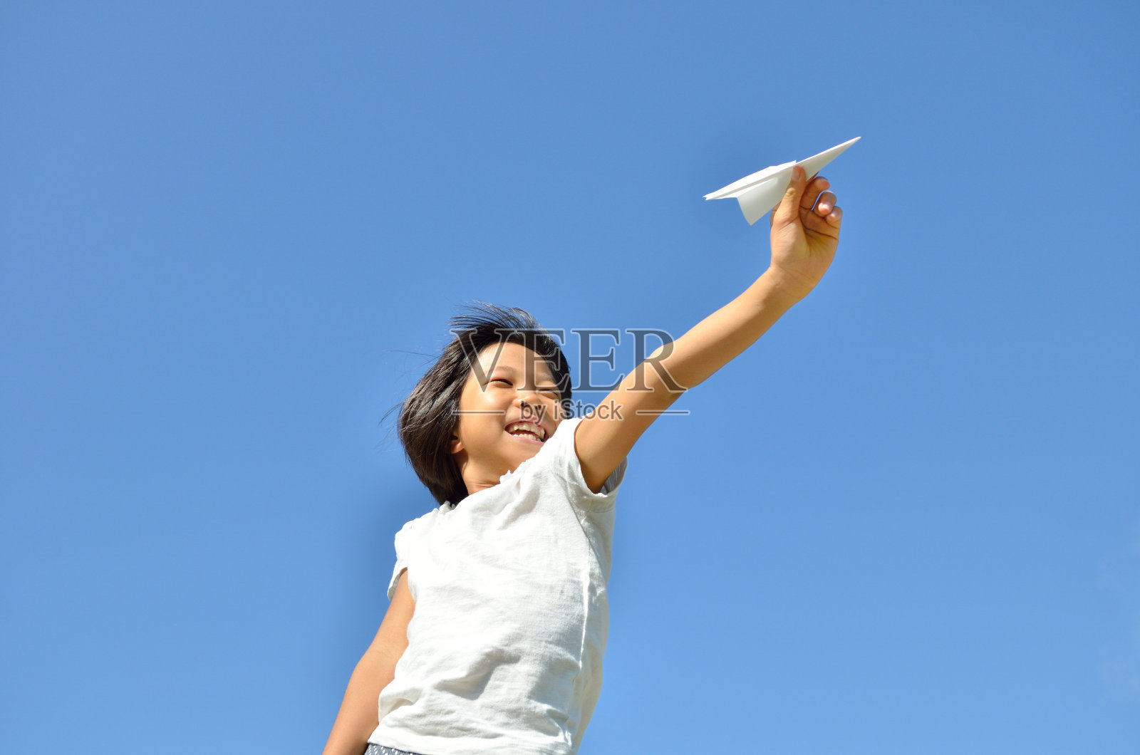 青空に紙飛行機を飛ばす女の子照片摄影图片