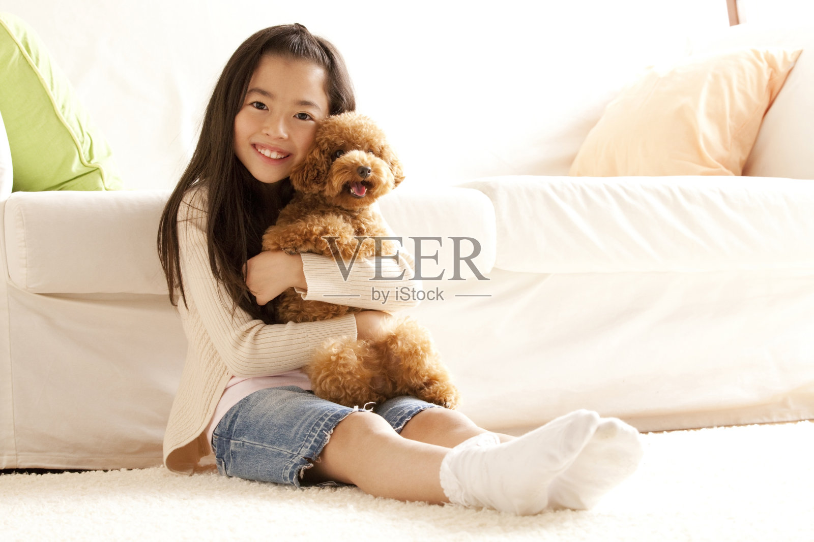 女孩微笑着抱着一只玩具狮子狗照片摄影图片