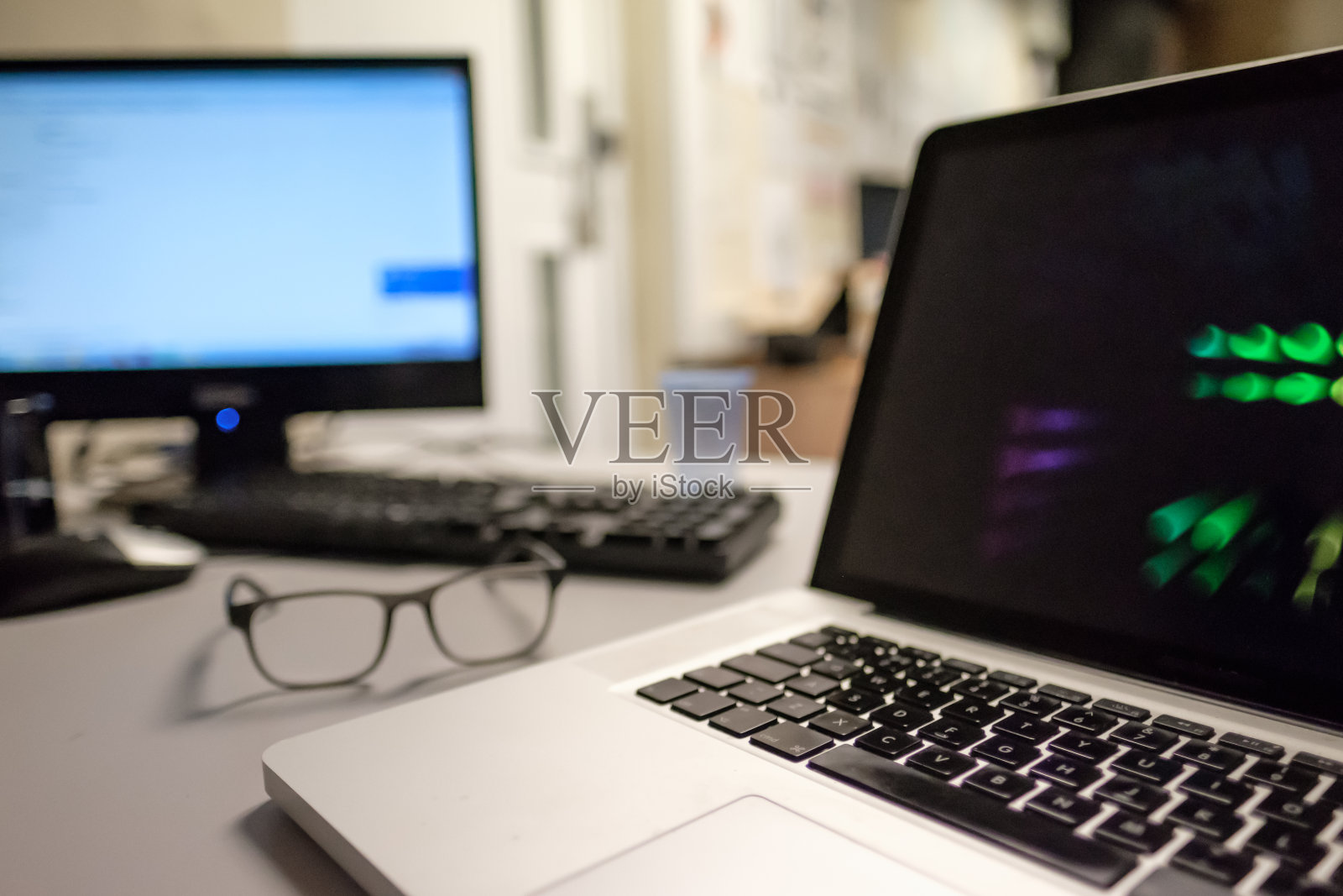 伦敦，英国，2017年2月27日:在繁忙的办公室里，一台现代的著名笔记本电脑和另一台服务器在后台。照片摄影图片