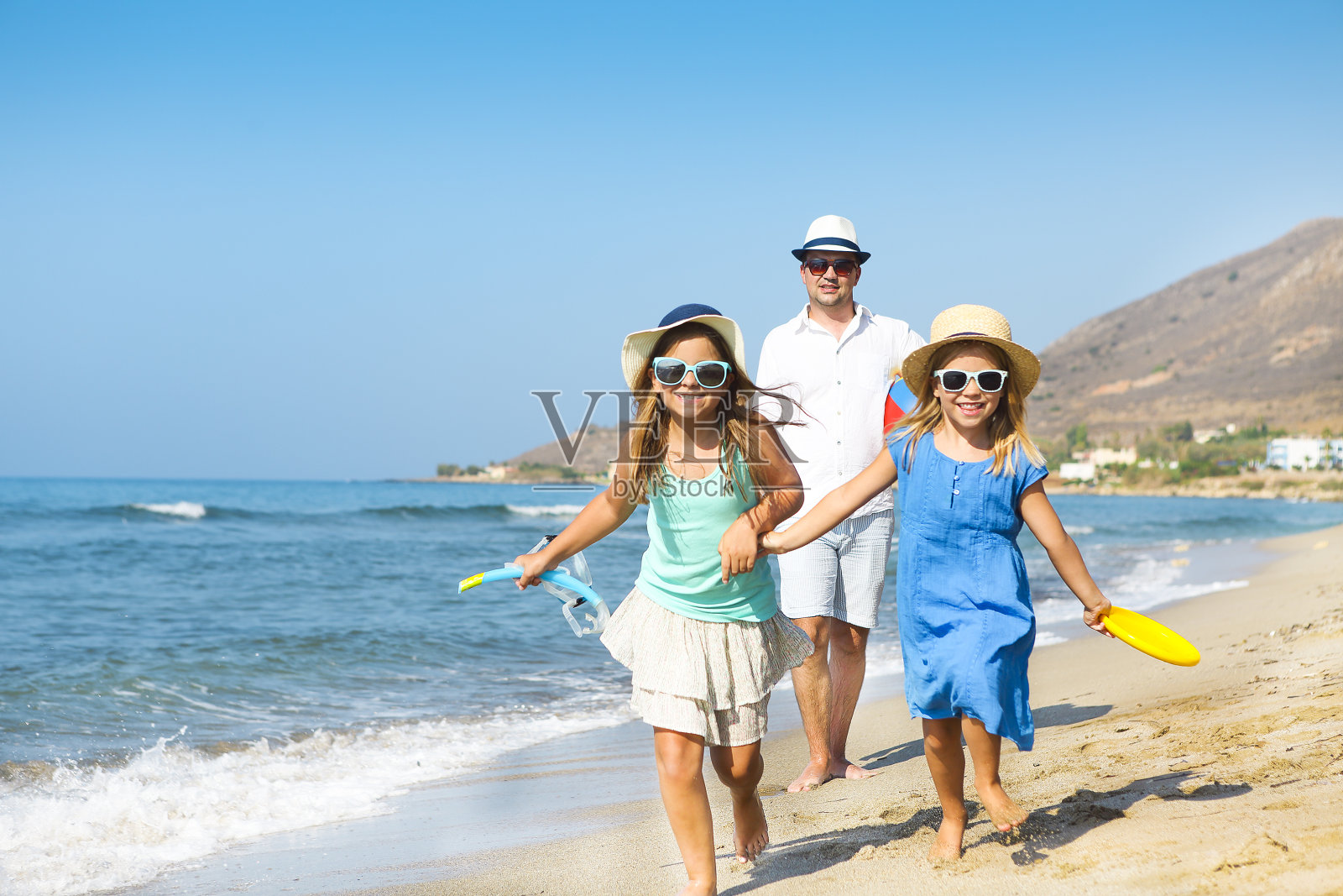 幸福的年轻的家庭在日落时在海滩上跑步。家庭旅游的概念照片摄影图片