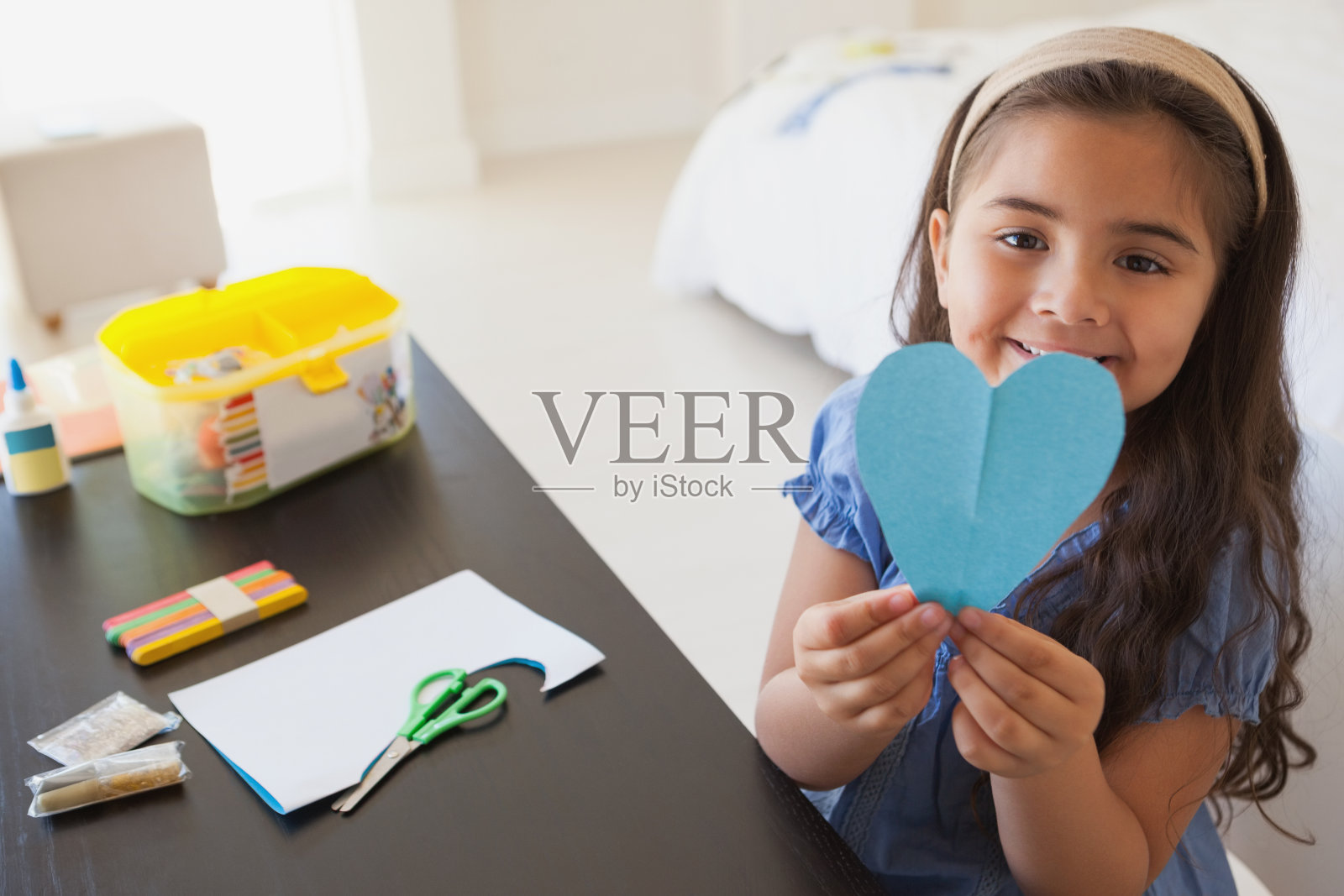 可爱的小女孩拿着心形的纸在桌子上照片摄影图片