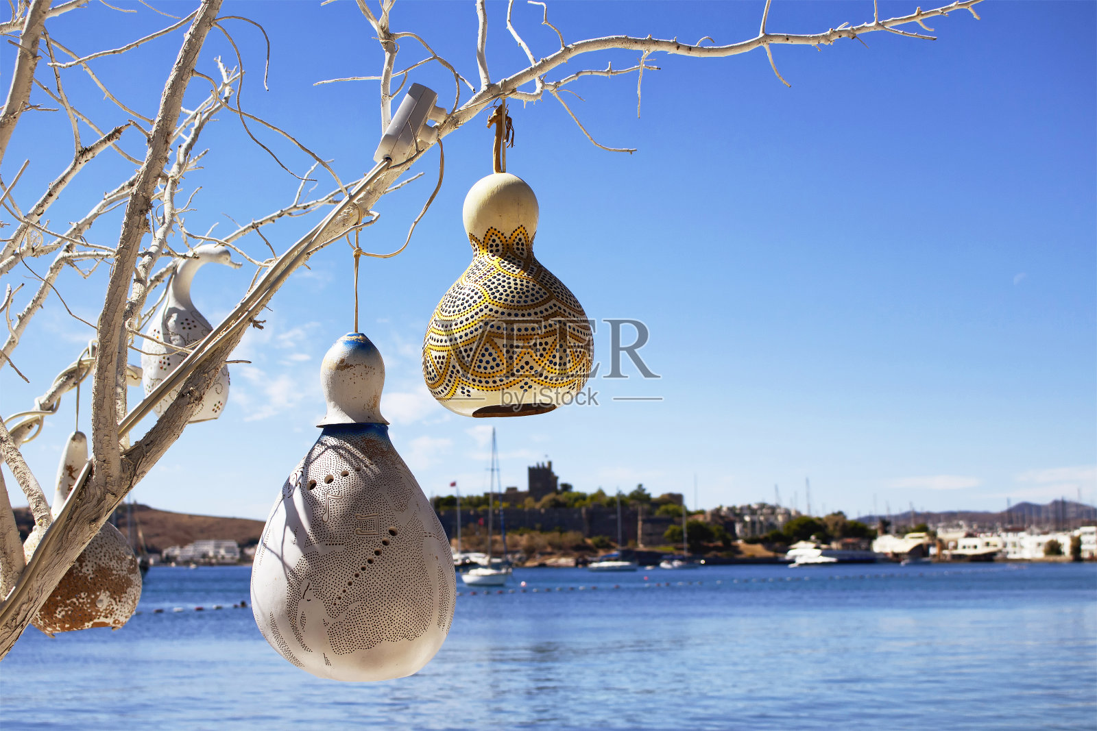 在土耳其博德鲁姆市的海边，用水南瓜(葫芦)手工制作的灯。背景是游艇、爱琴海和博德鲁姆城堡。这些灯饰用于该地区的装饰。照片摄影图片