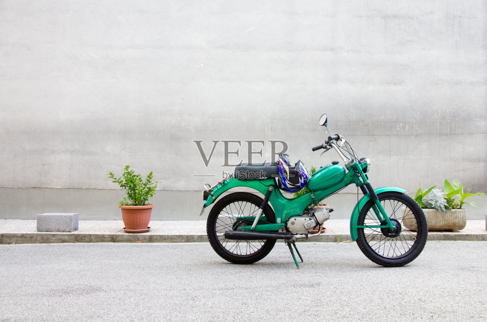 绿色的摩托车靠在混凝土墙上照片摄影图片