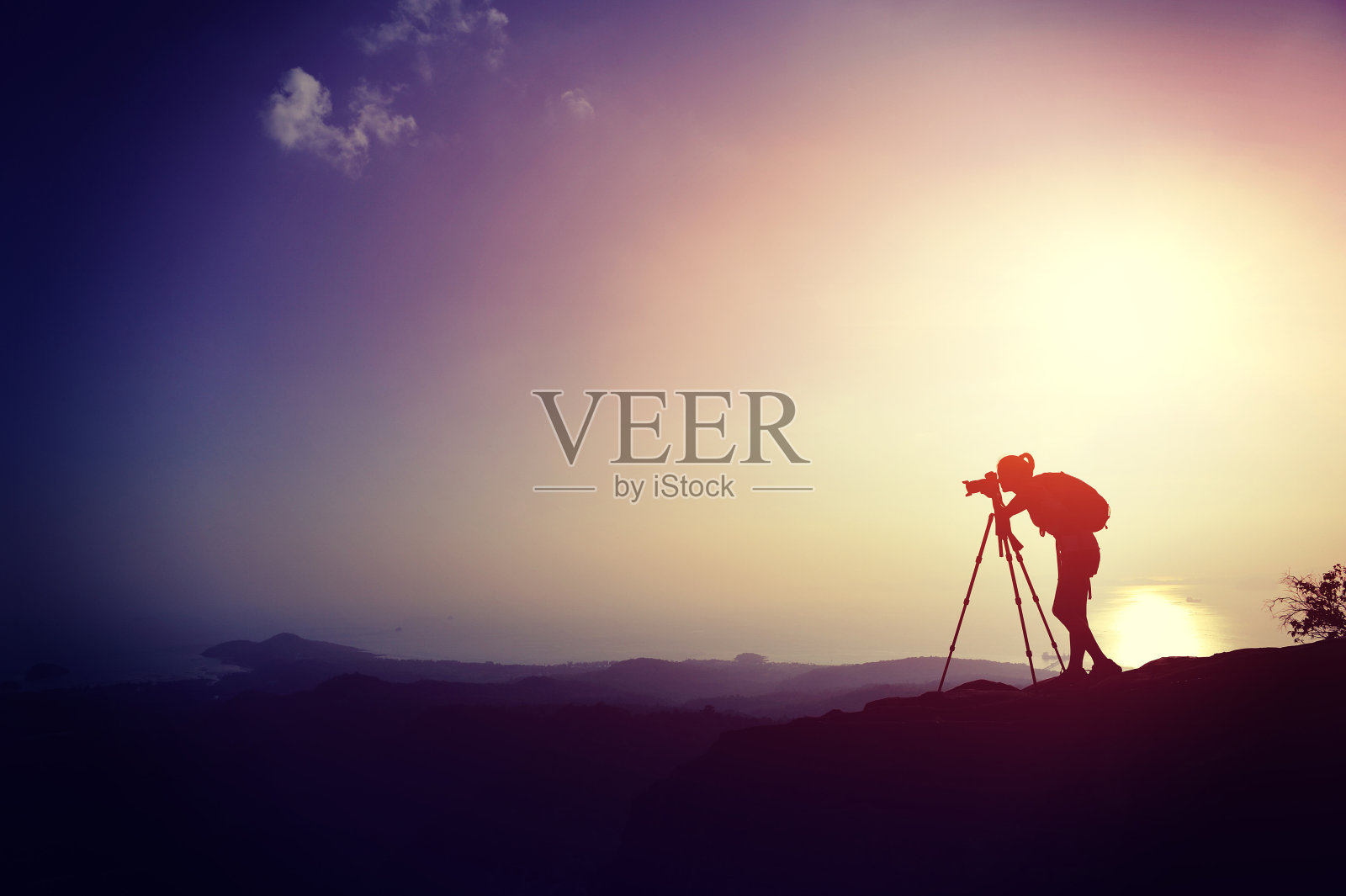日落时分，山顶上女摄影师的剪影照片摄影图片