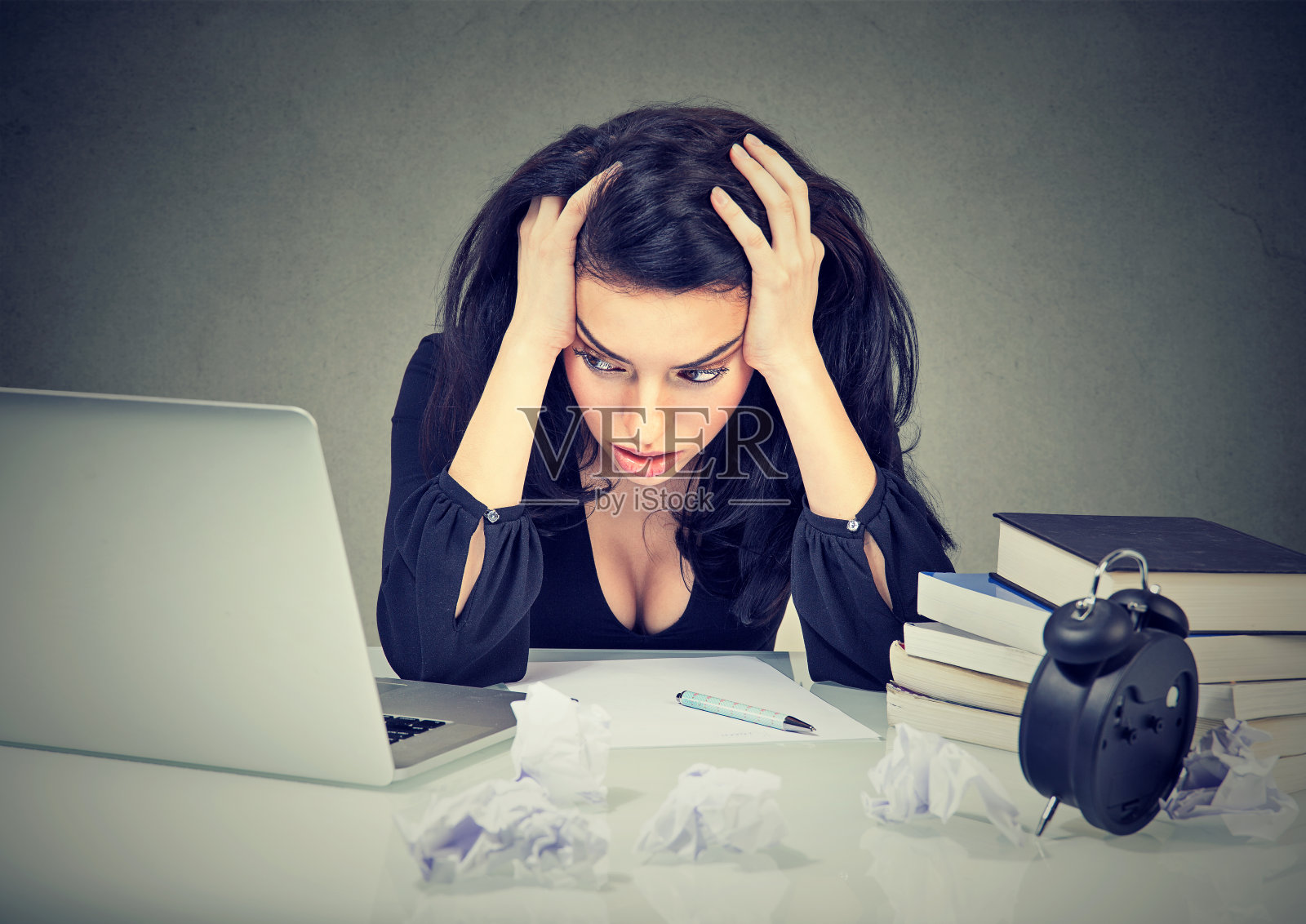 太多工作压力的女人坐在她的书桌前，在笔记本电脑前看书照片摄影图片