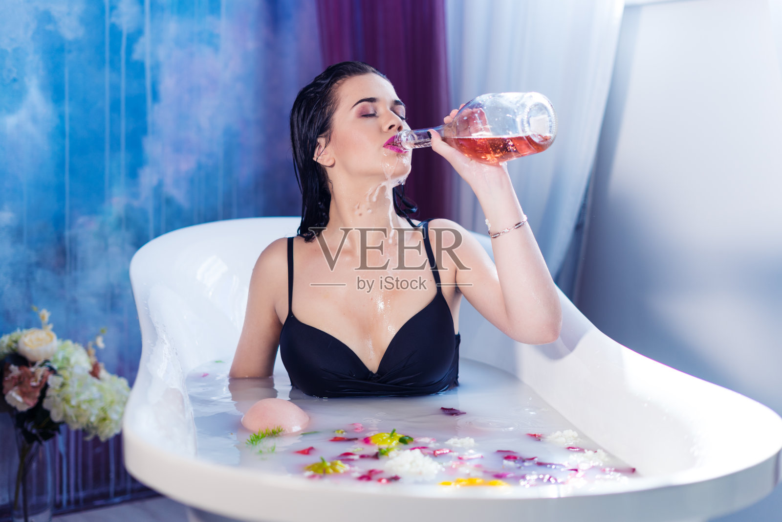 性感的黑发女人喝香槟，同时洗热水澡照片摄影图片