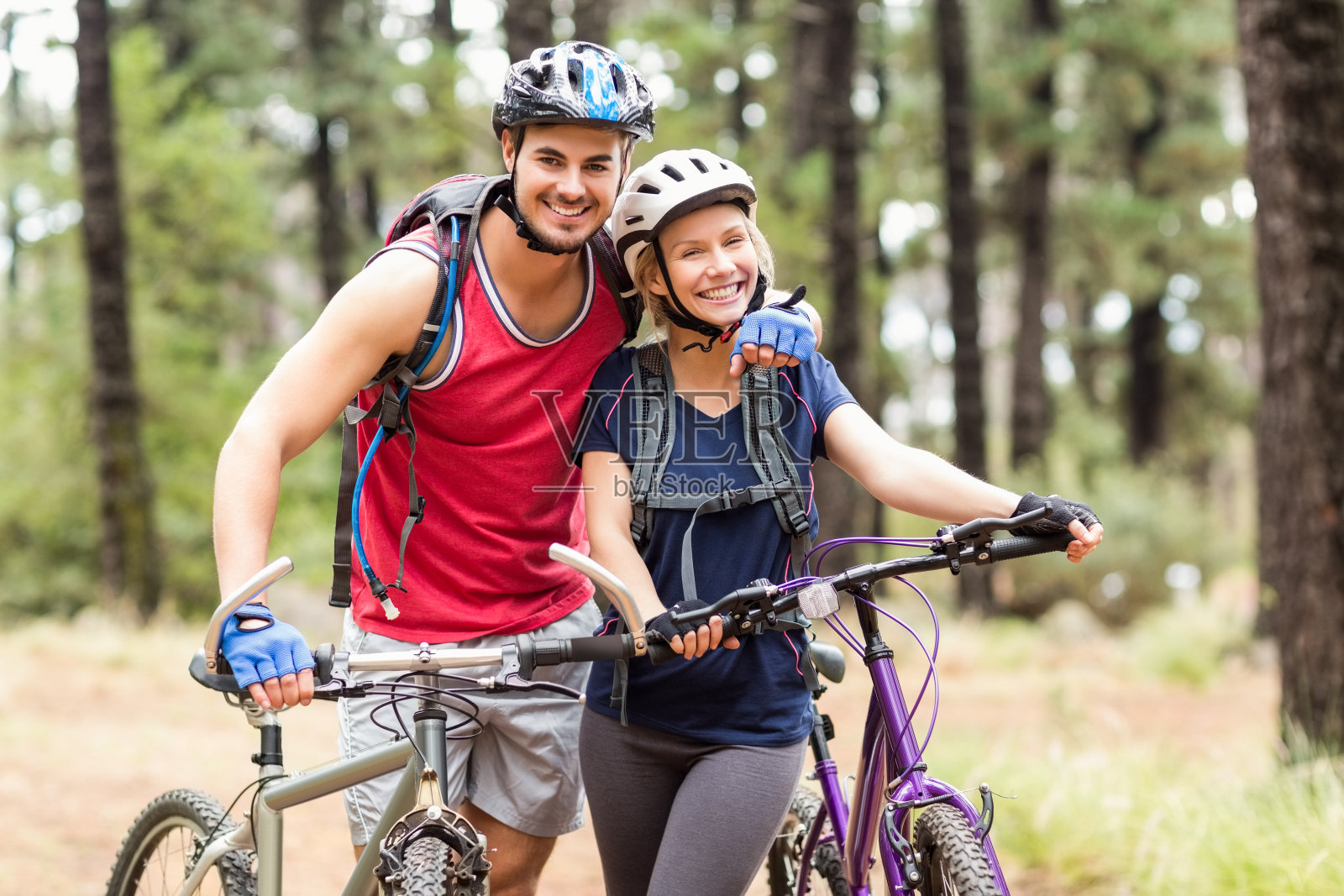 一对快乐的骑自行车的年轻夫妇看着镜头照片摄影图片