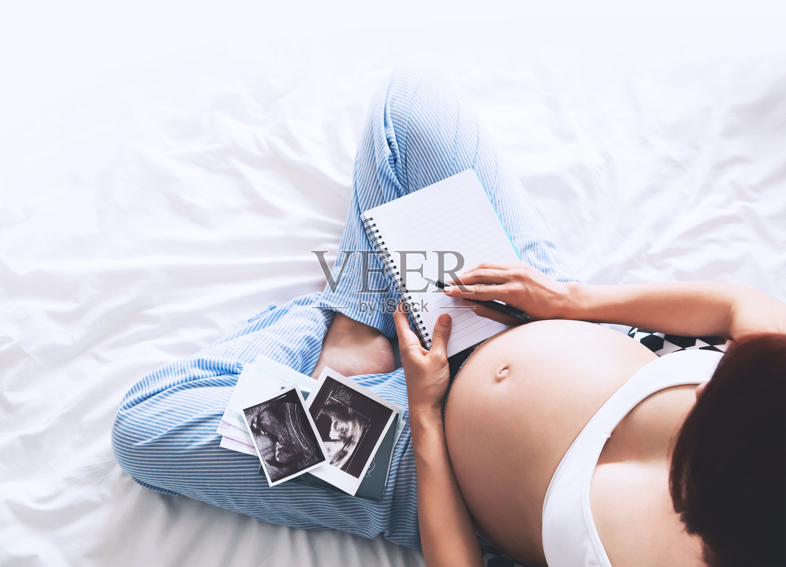 孕妇在笔记本上做笔记，拿着超声图像和医疗文件照片摄影图片