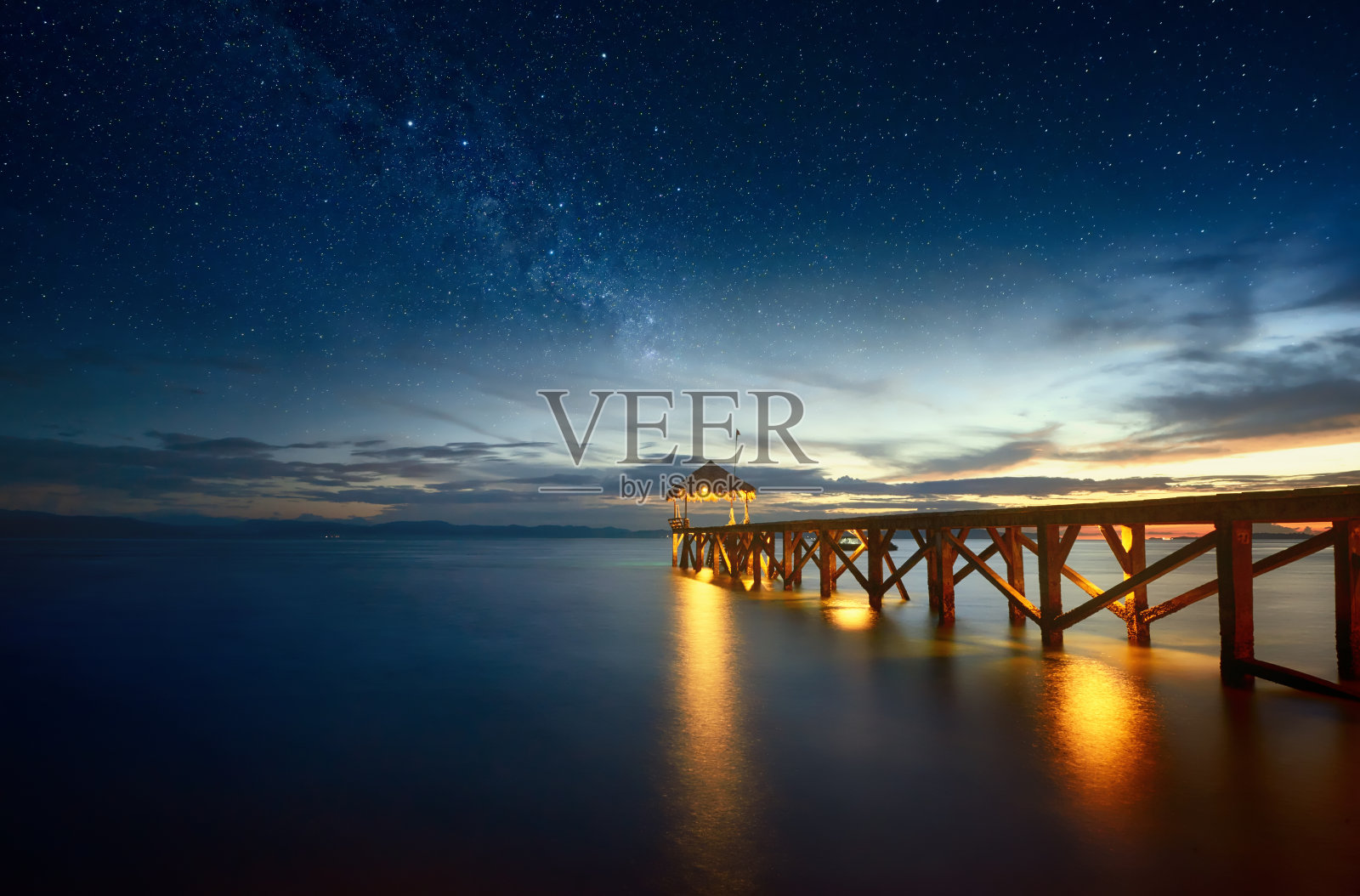 美丽的夜晚海景，银河的天空和码头延伸到海洋。照片摄影图片