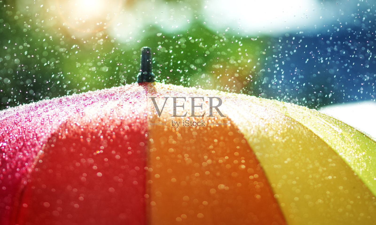 雨点落在带彩虹色彩的雨伞上照片摄影图片