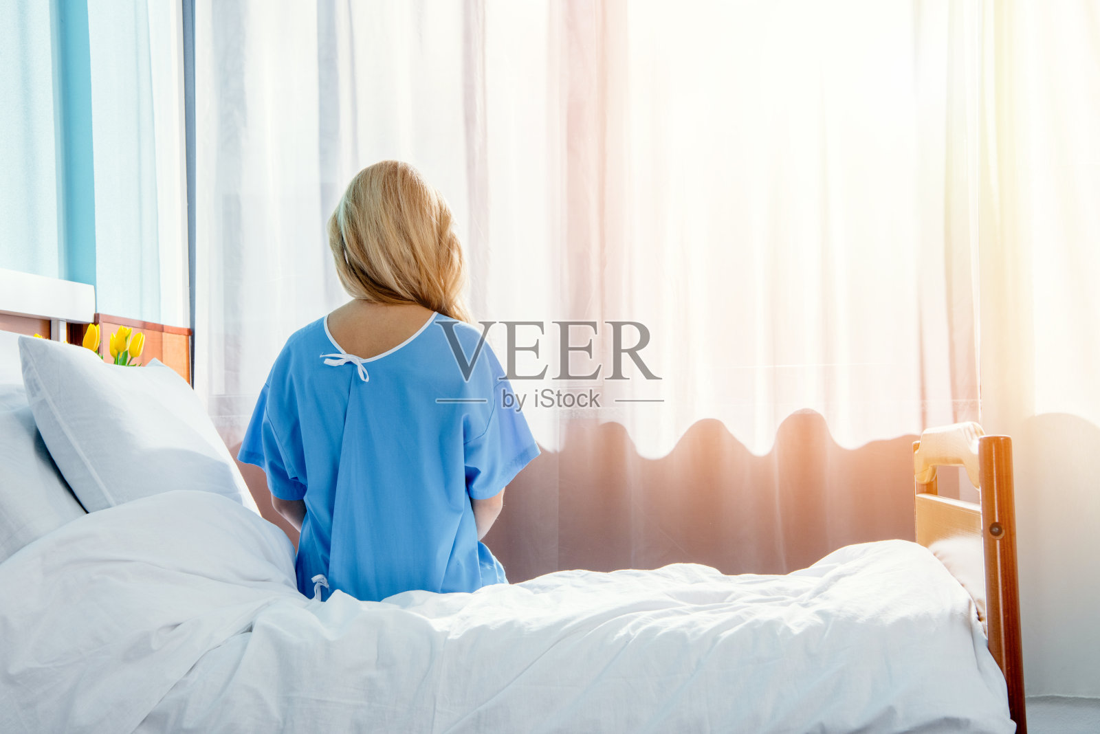 一位妇女坐在医院病房床上的背影照片摄影图片