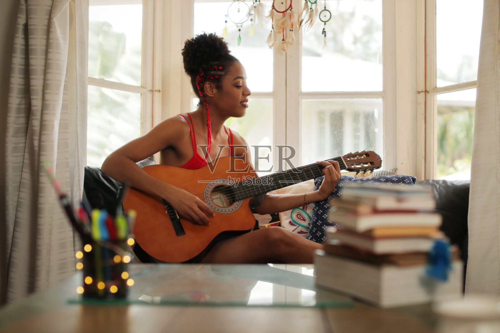 混血女孩在家里唱歌和弹古典吉他照片摄影图片
