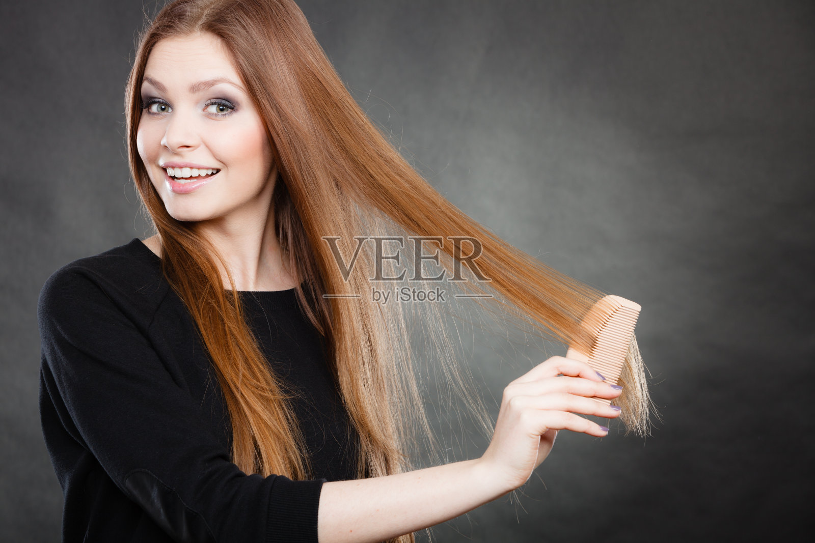 长发女孩梳理着她美丽的头发。照片摄影图片
