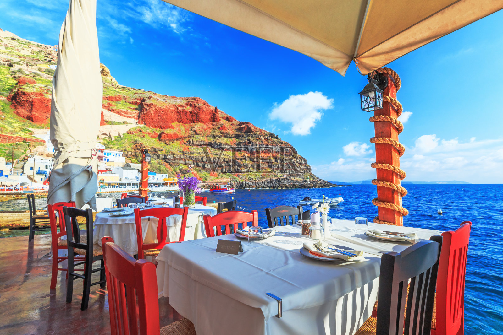 在希腊，欧洲的圣托里尼岛度假胜地，在海边对着蓝色的海水的爱琴海的餐厅。照片摄影图片