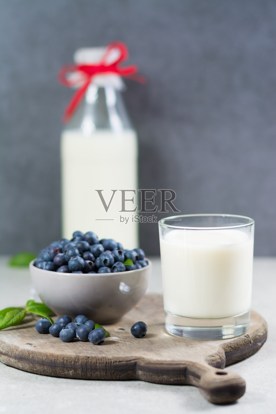新鲜采摘的绿叶蓝莓和新鲜牛奶。木背景上的越桔。蓝莓抗氧化。健康饮食和营养的概念照片摄影图片
