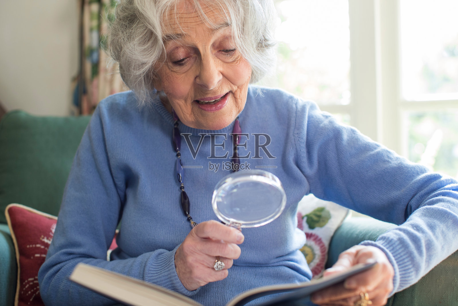 老年妇女在家用放大镜看书照片摄影图片