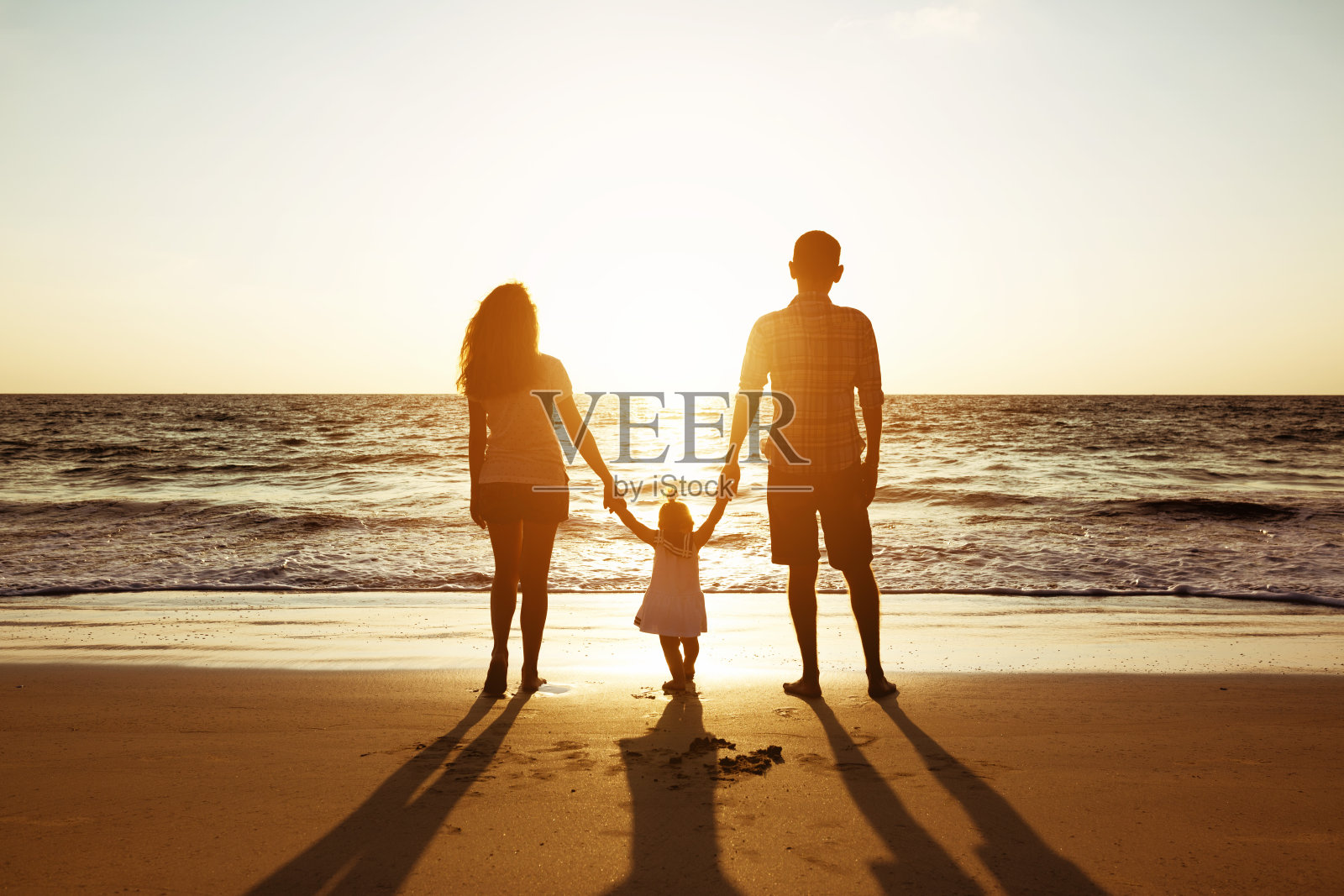 父亲母亲和女儿的家庭日落海剪影照片摄影图片