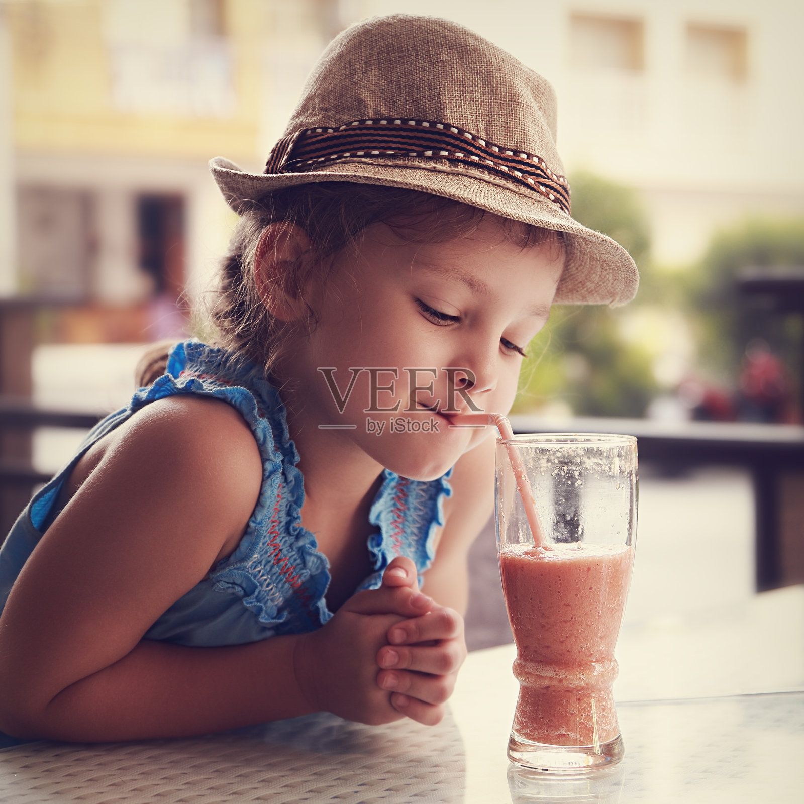 可爱的小女孩在街头餐厅喝着美味的果汁照片摄影图片