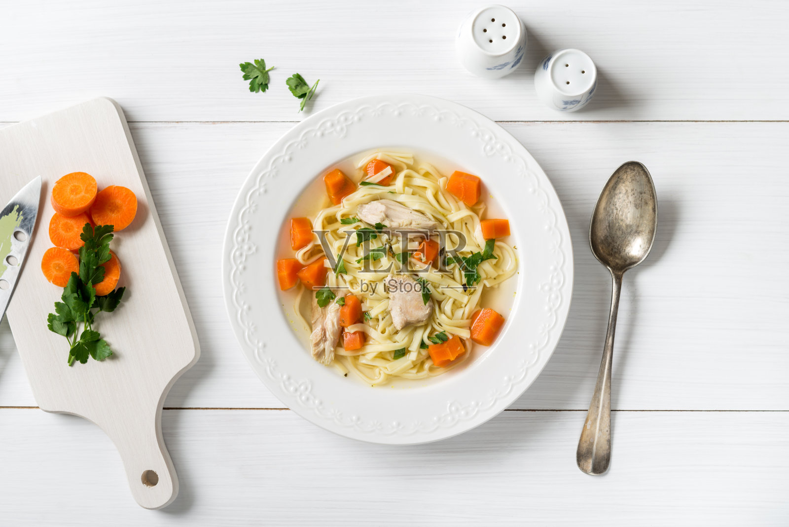 白色餐桌上的鸡汤、意大利面、胡萝卜和欧芹照片摄影图片