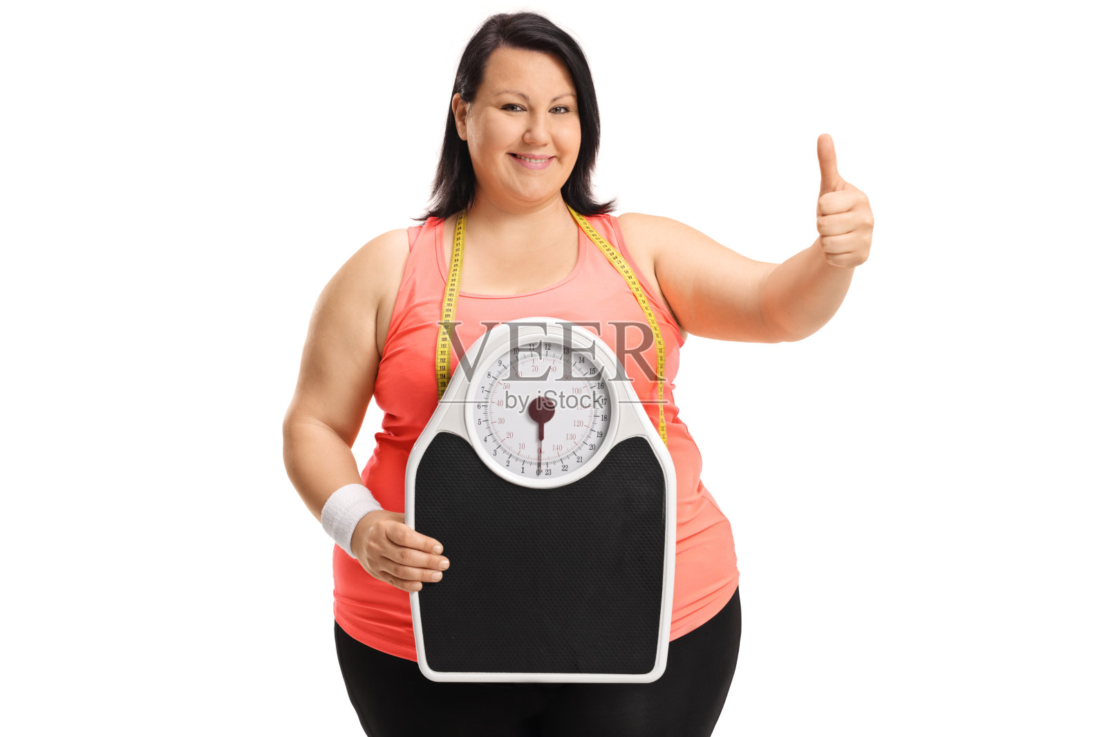超重的女人拿着体重秤，竖起大拇指照片摄影图片