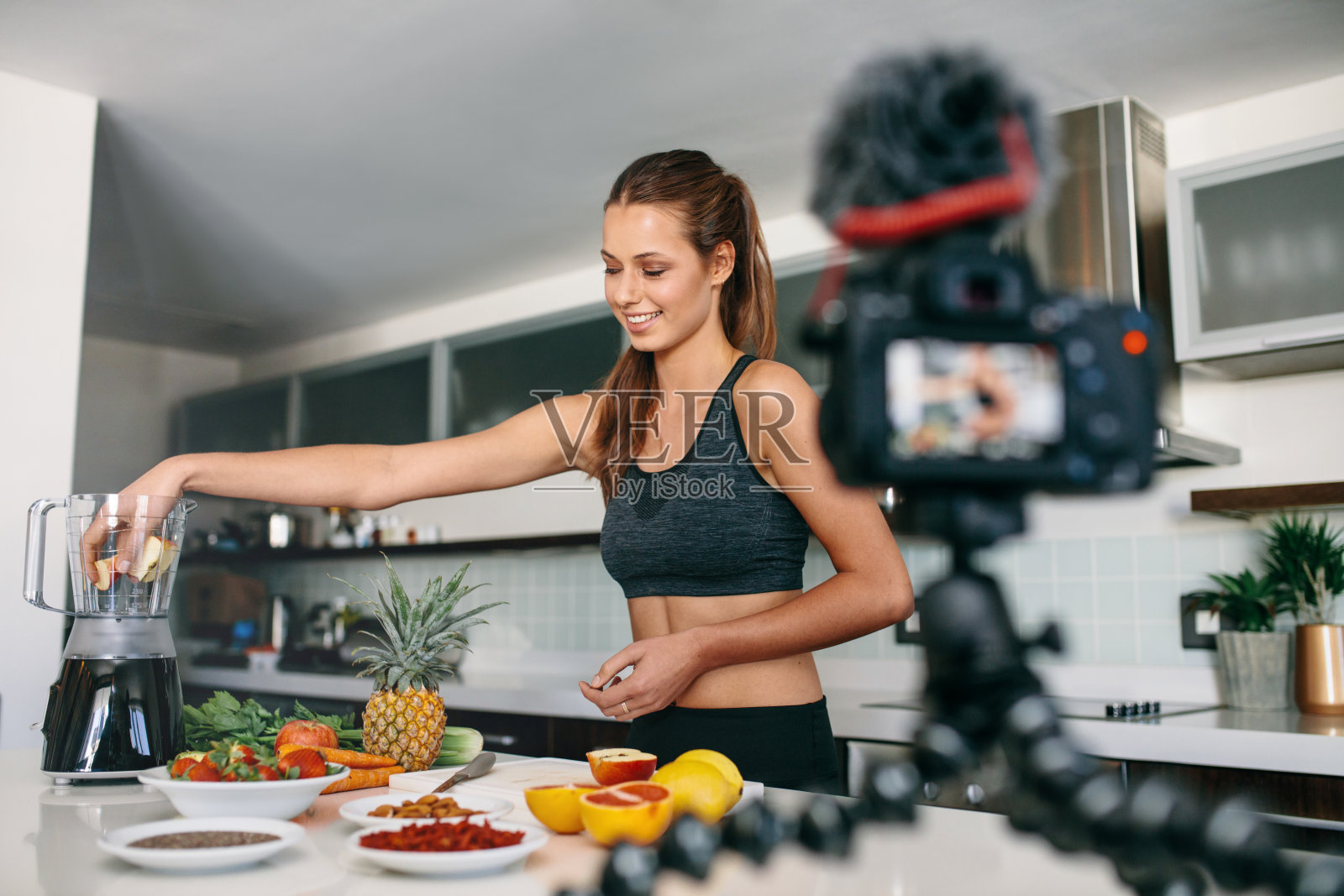 年轻女性博客录制内容的视频博客在厨房。照片摄影图片