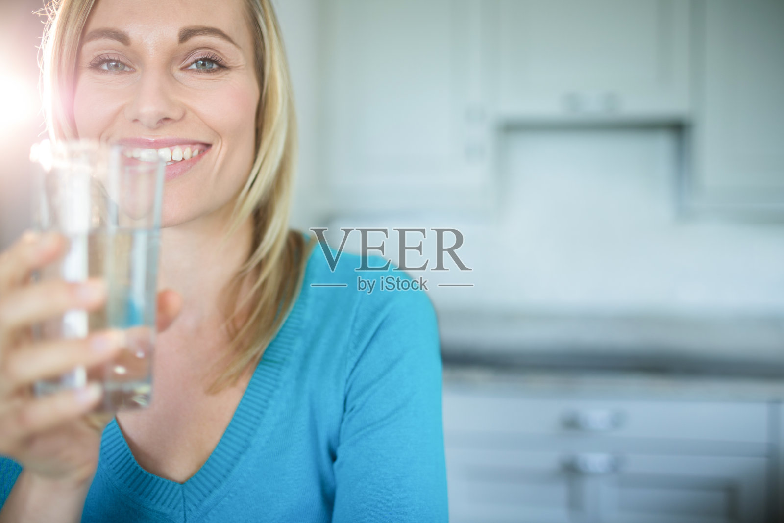 一个金发美女在喝一杯水照片摄影图片