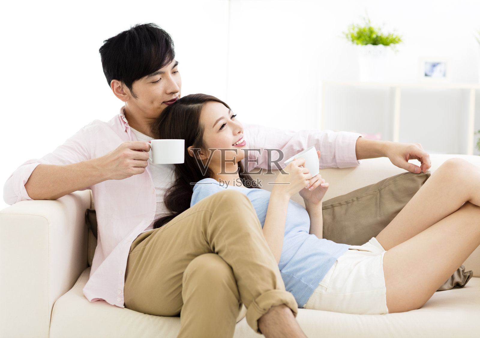 微笑的年轻夫妇坐在沙发上的肖像照片摄影图片