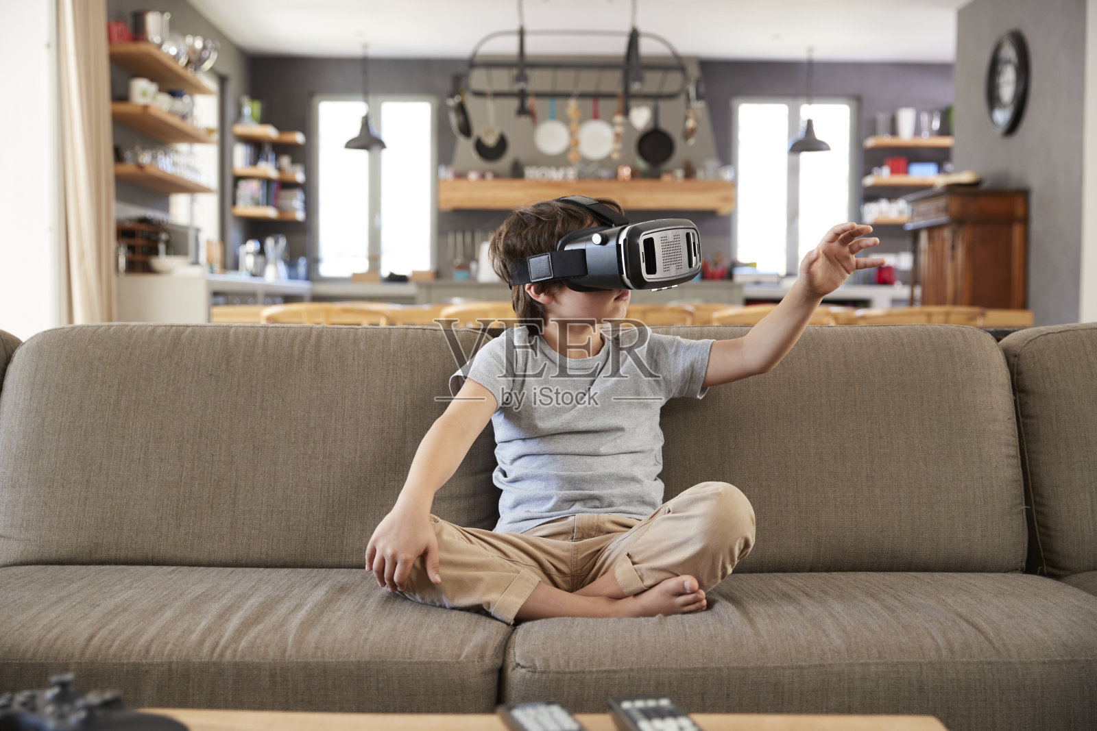 坐在沙发上戴着虚拟现实耳机的男孩照片摄影图片