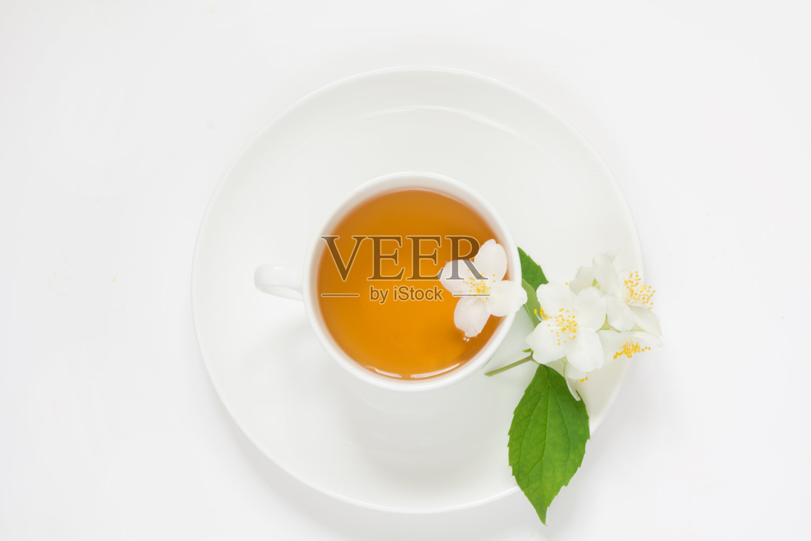 白色背景上的茉莉花和一杯绿茶。俯视图和概念。照片摄影图片