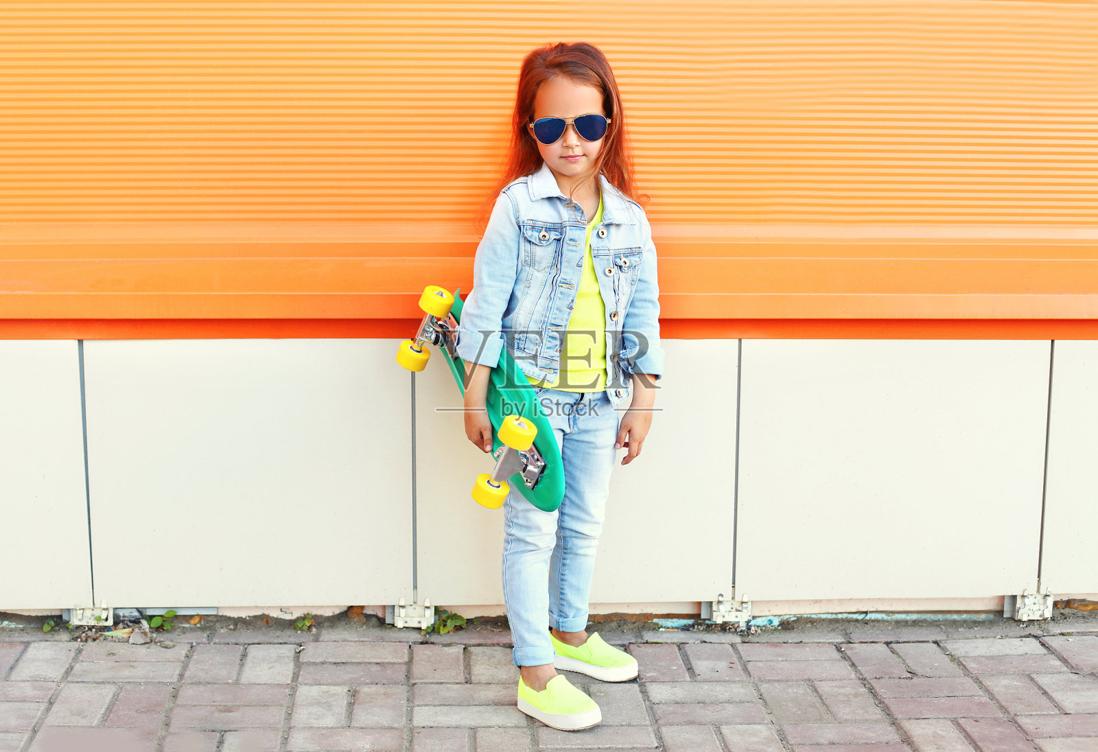 漂亮的小女孩与滑板在橙色的背景照片摄影图片
