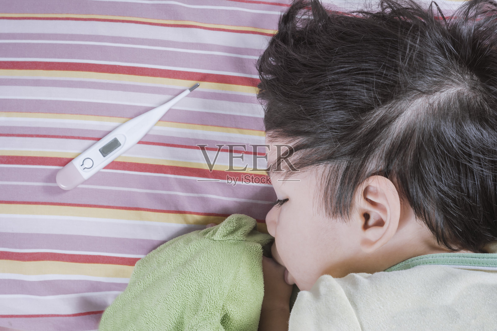 体温计和亚洲男婴病在床上。照片摄影图片