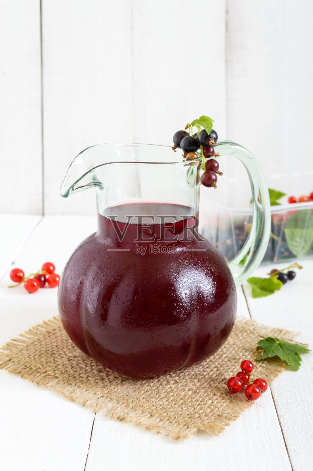 凉爽的夏季饮料与浆果-果盘在一个罐子在白色的木制背景。垂直的观点。照片摄影图片
