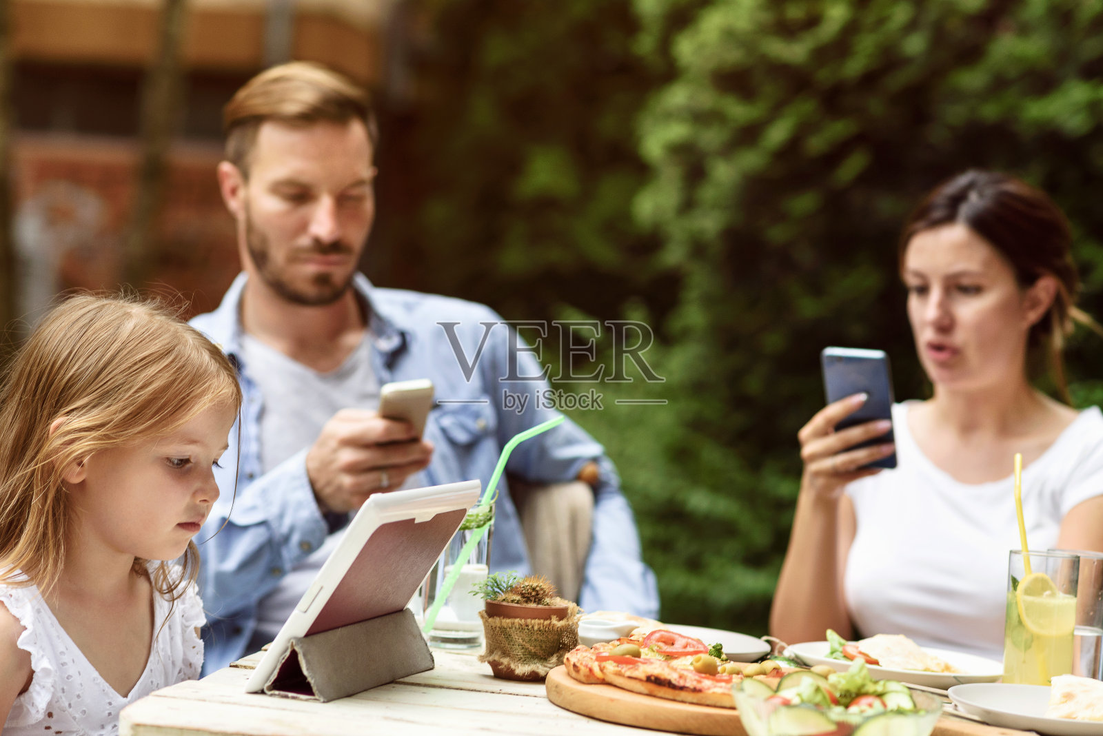 在午餐桌上使用数码科技的家庭照片摄影图片