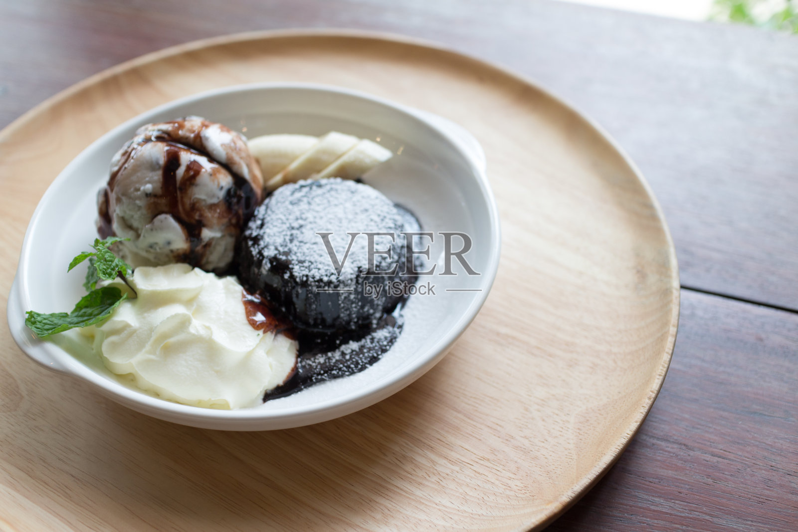 巧克力熔岩蛋糕，香草冰淇淋球，香蕉和鲜奶油照片摄影图片