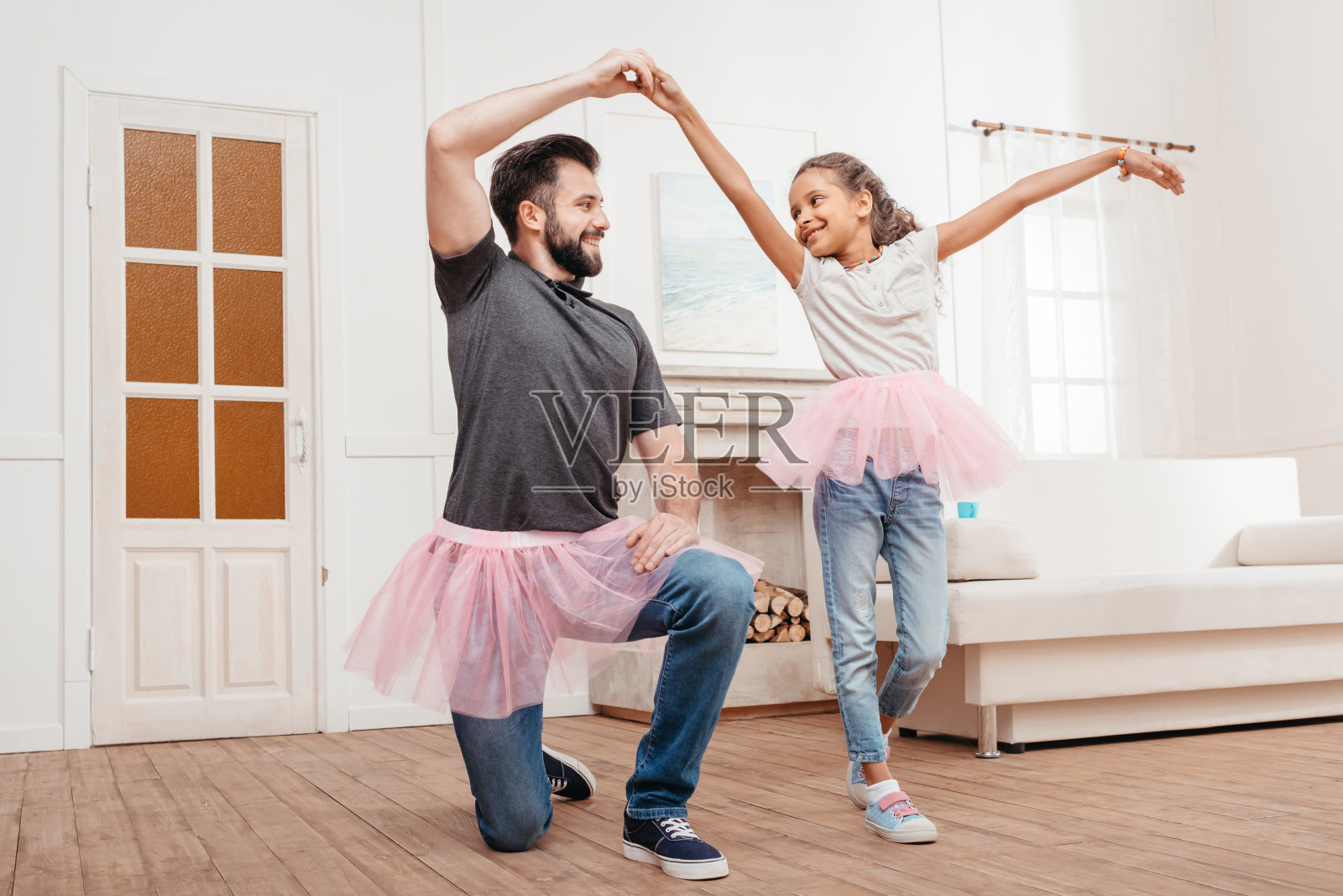 多文化背景的父女穿着粉红色的薄纱短裙在家跳舞照片摄影图片
