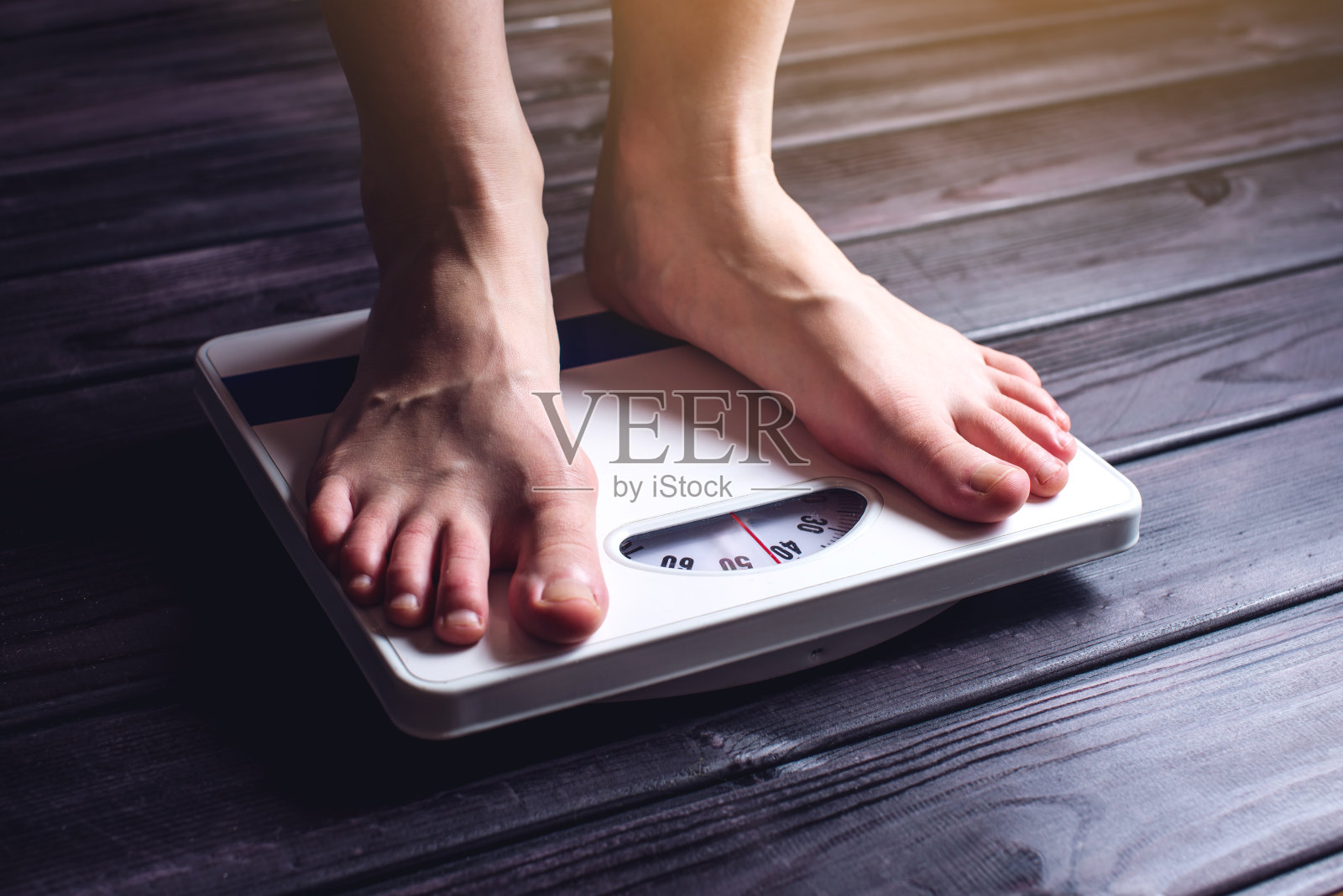 为了控制体重，女人的脚被放在机械秤上照片摄影图片