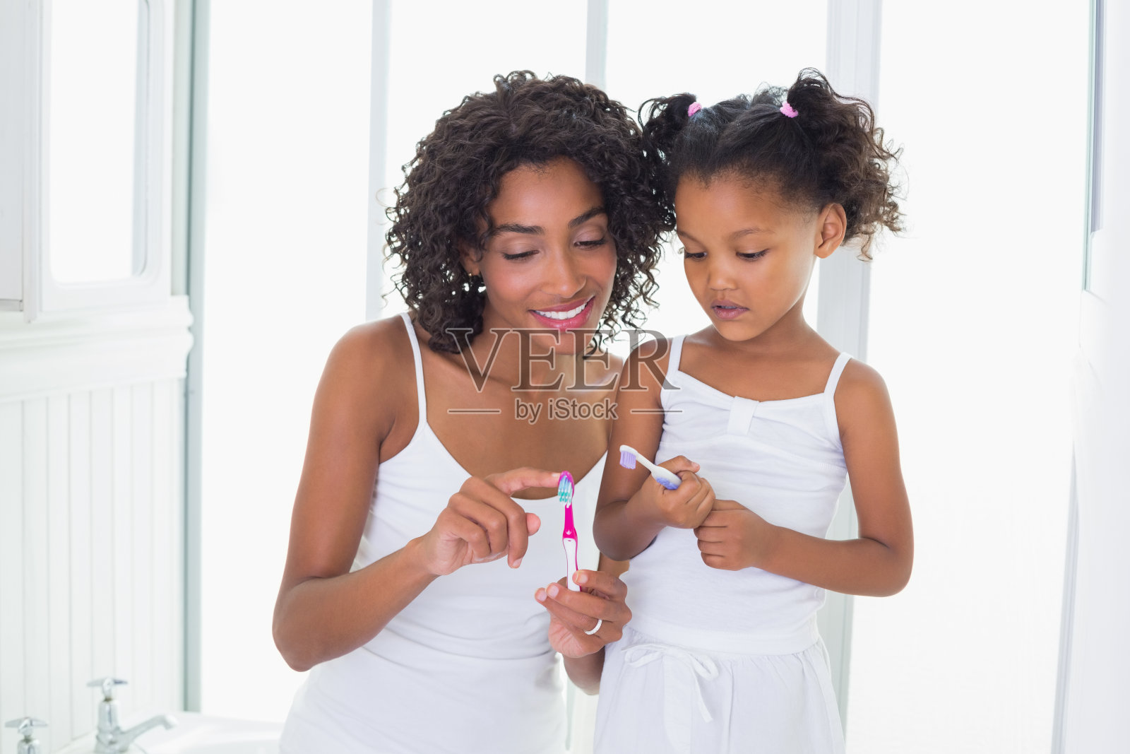 漂亮妈妈给女儿看她的牙刷照片摄影图片