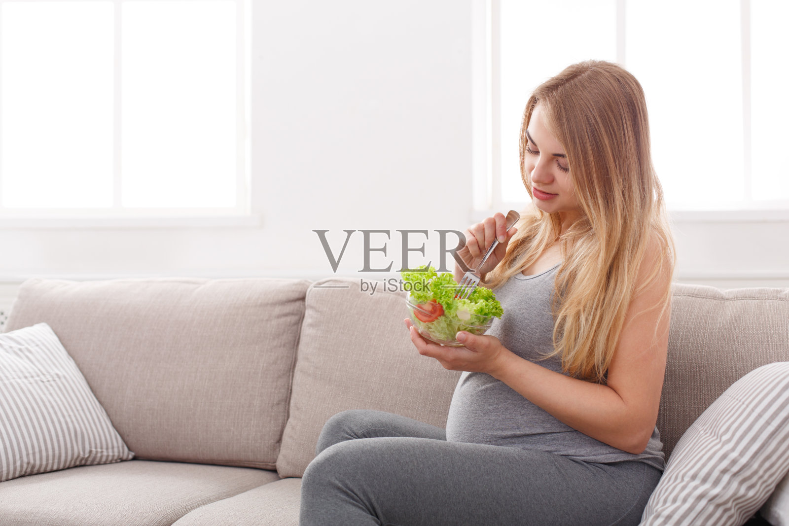 年轻孕妇吃新鲜的绿色沙拉照片摄影图片