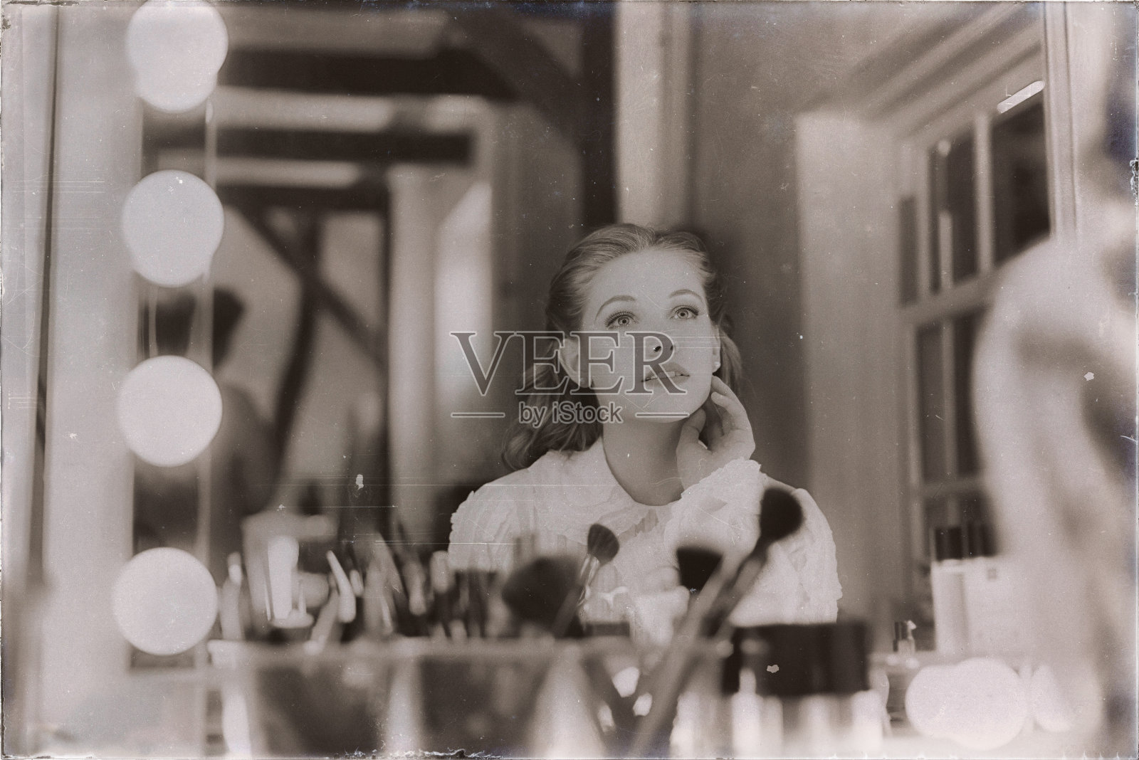 20世纪40年代的一张怀旧照片，梦幻般的年轻女子看着剧院的镜子。照片摄影图片