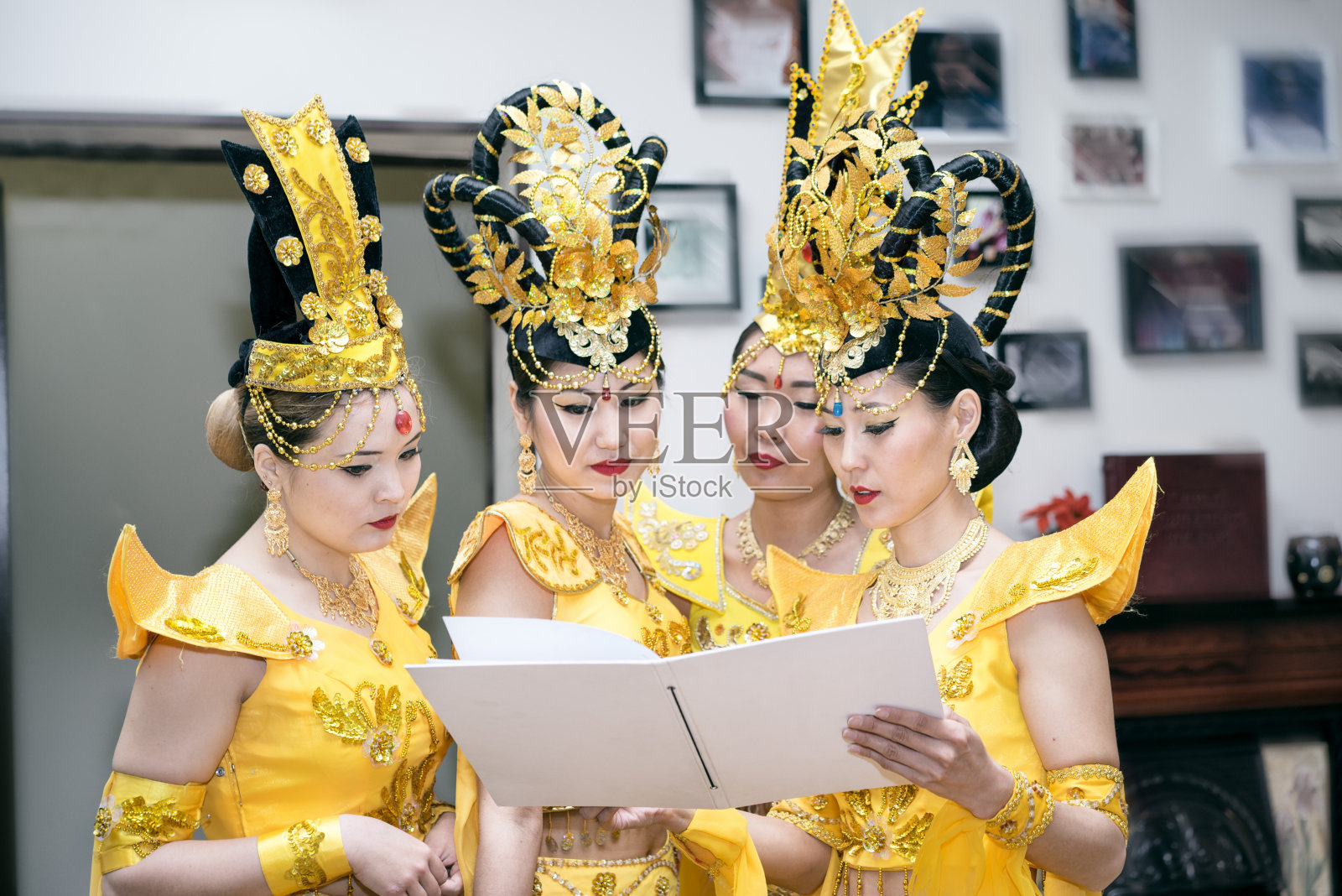 四位亚洲女演员穿着泰国传统的黄色服装读着空白的课本照片摄影图片
