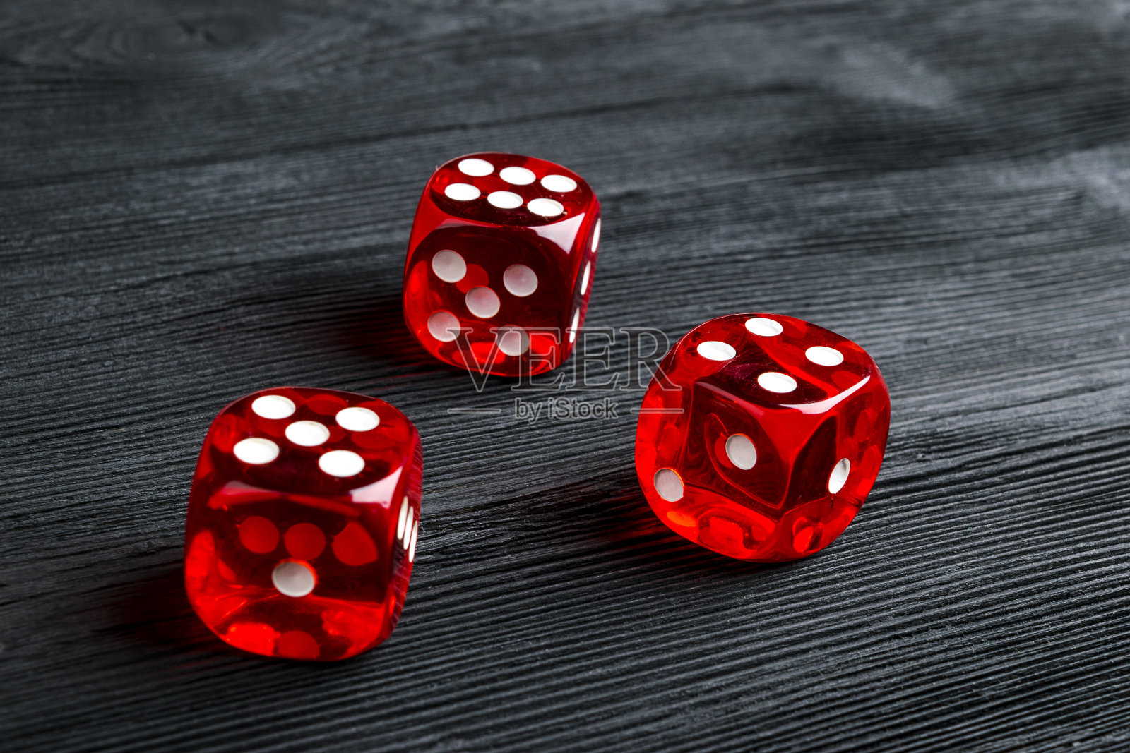 风险概念-玩骰子在黑色木制背景。用骰子玩游戏红色的赌场骰子。滚动骰子的概念商业风险，机会，好运或赌博照片摄影图片