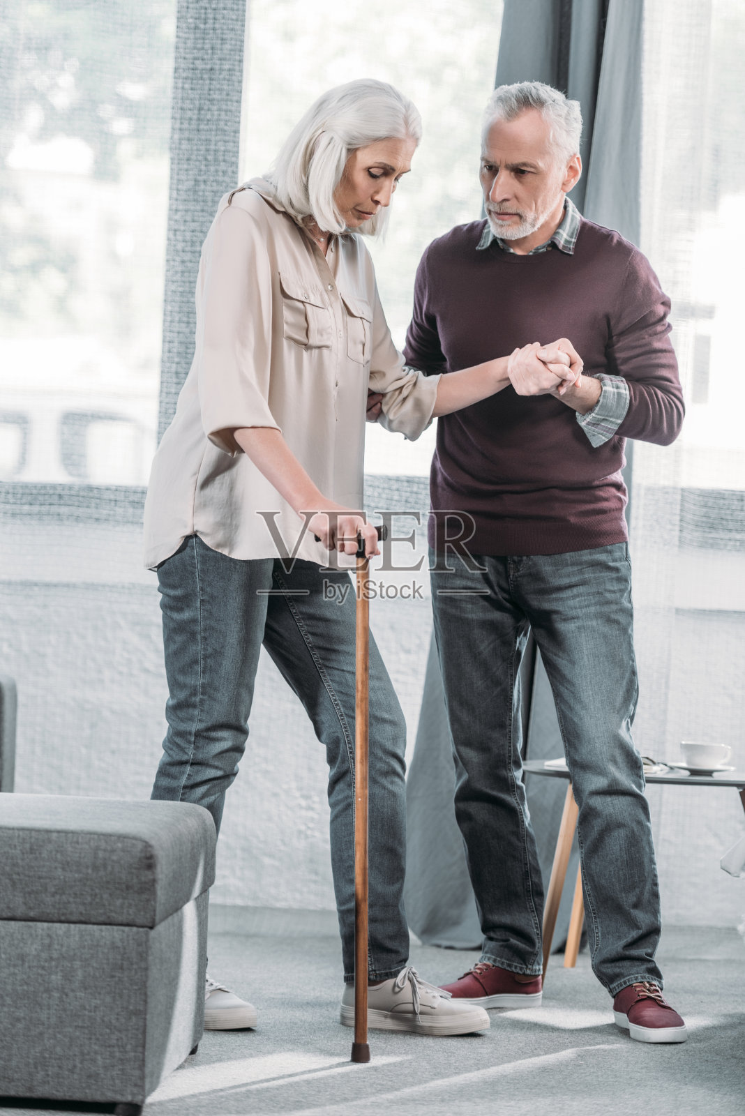 一名男子在家帮助拄着拐杖的老伴走路照片摄影图片
