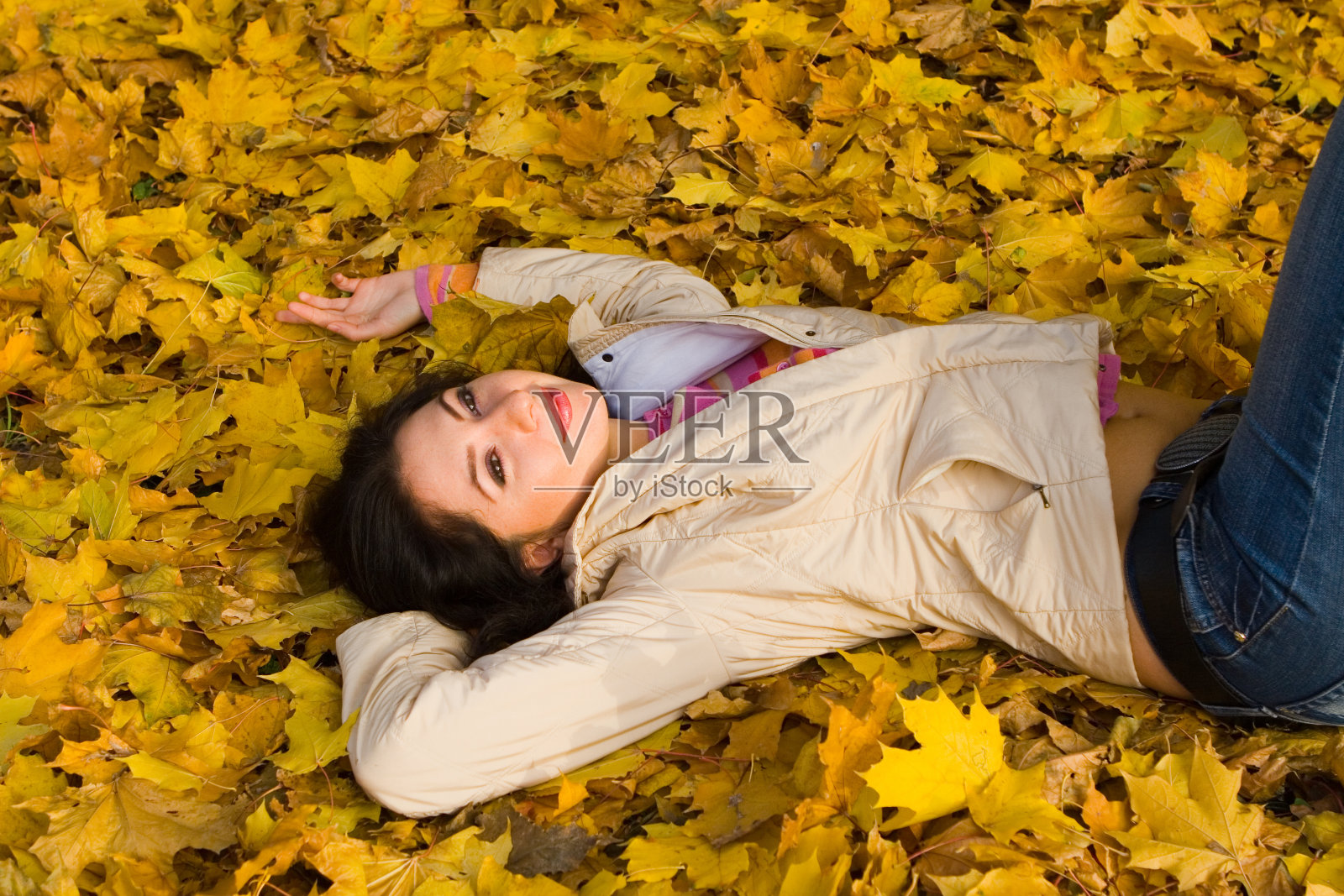 年轻漂亮的女人在秋叶上休息照片摄影图片
